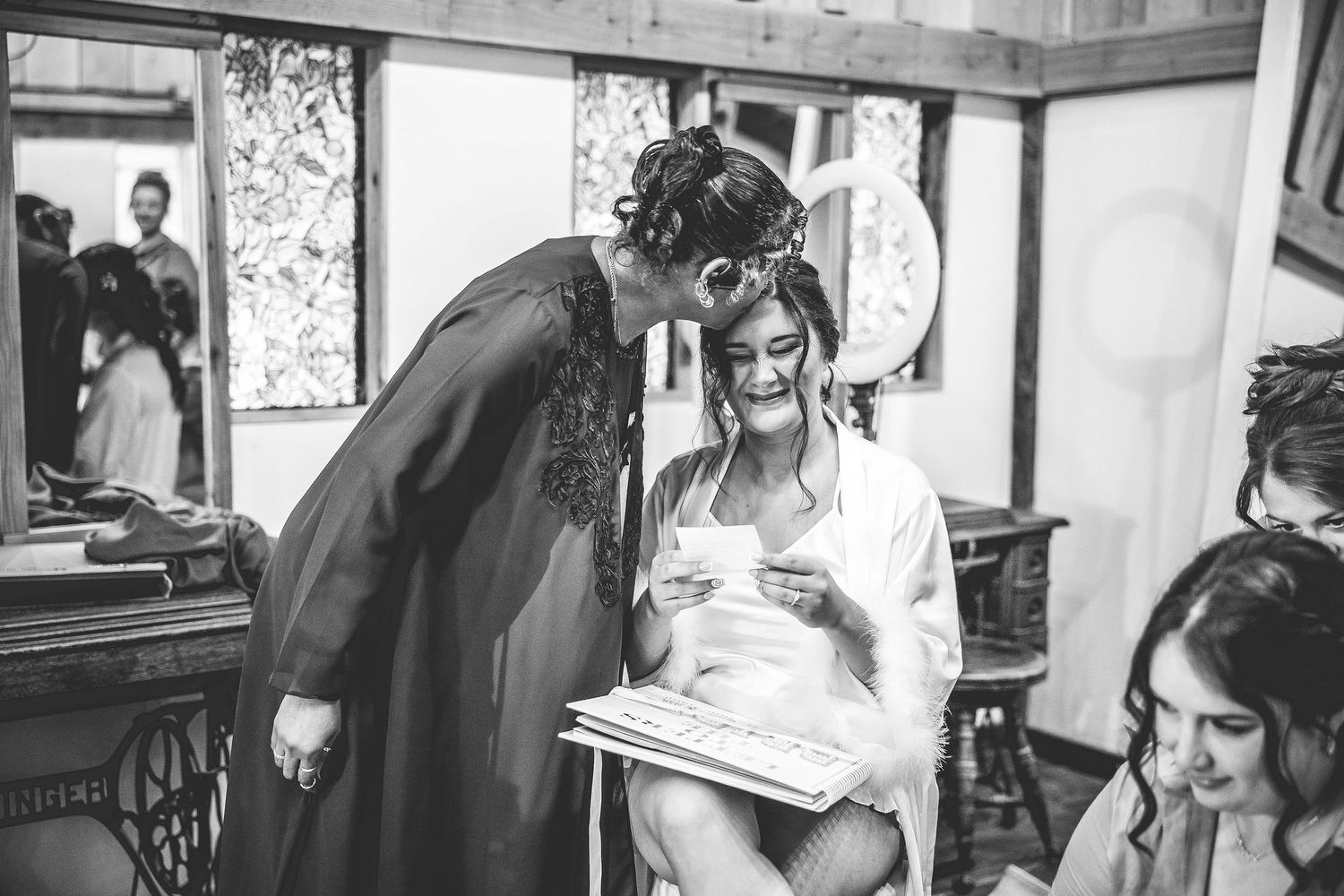 Black and white candid moment during wedding preparations in a vintage-style room.
