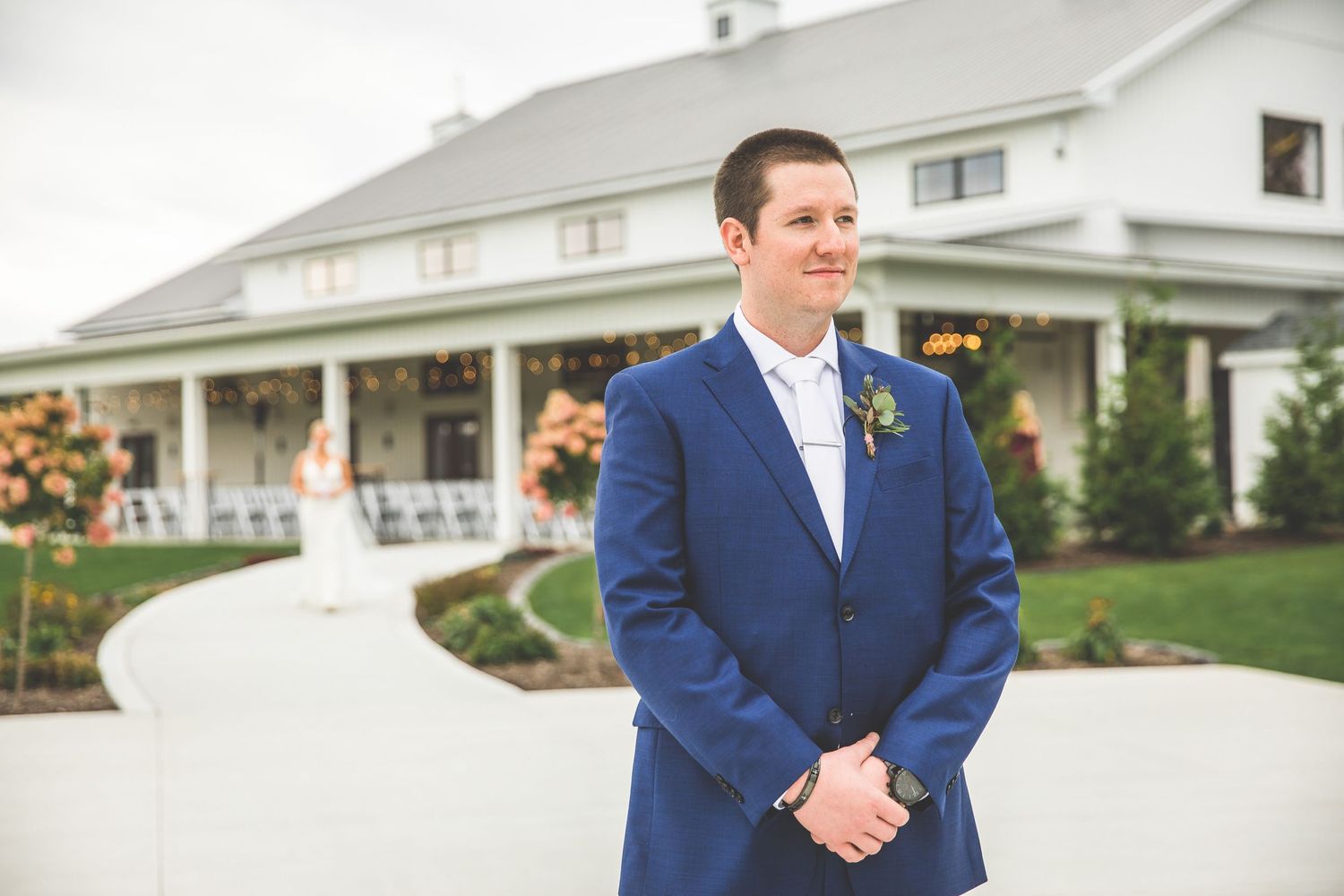 Groom in navy suit walking outside white building on wedding day.