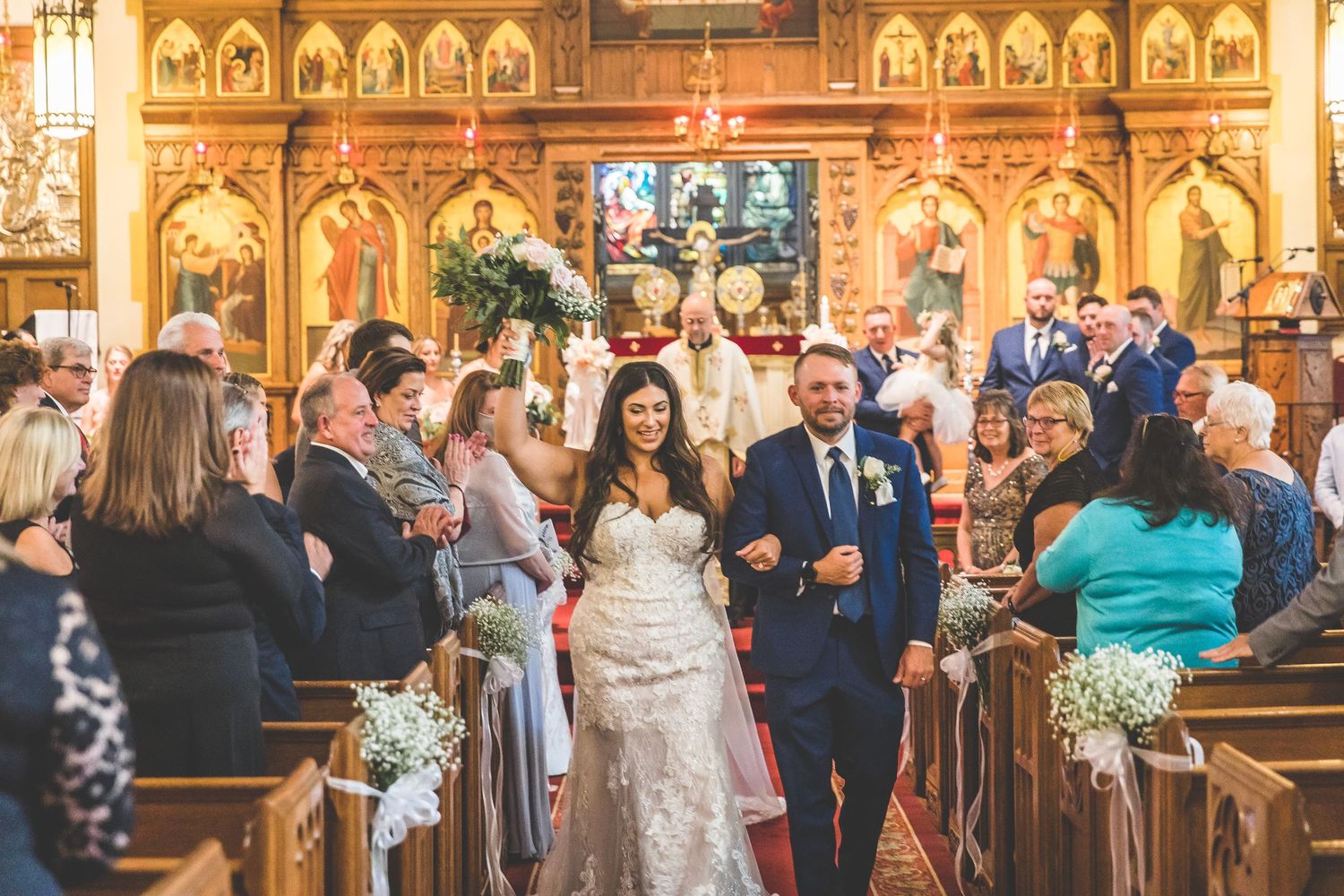 Wedding guests gather in an ornate church interior with gothic architecture and decorative details.