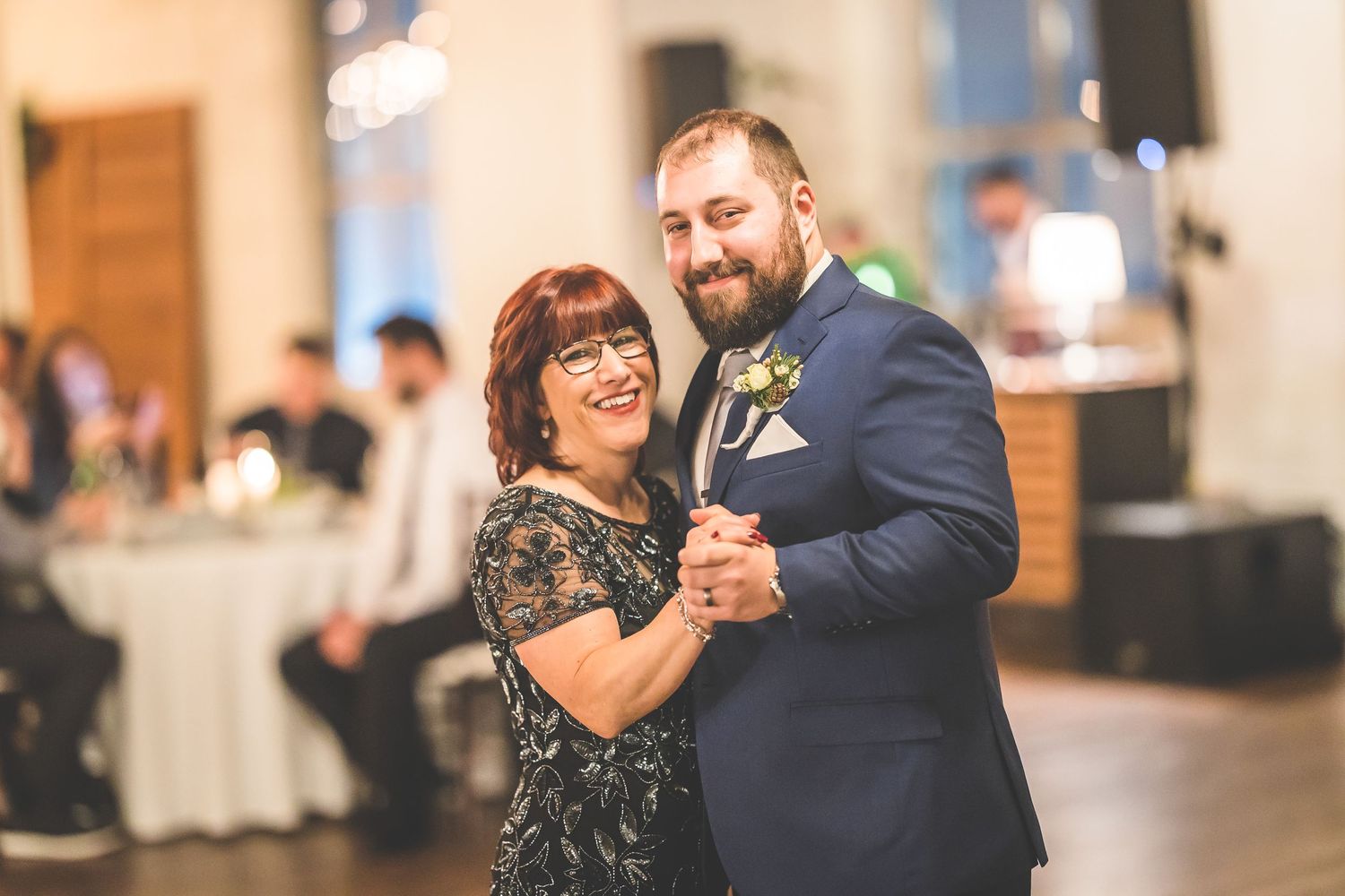 Couples sharing emotional dances during a wedding reception under warm lighting.