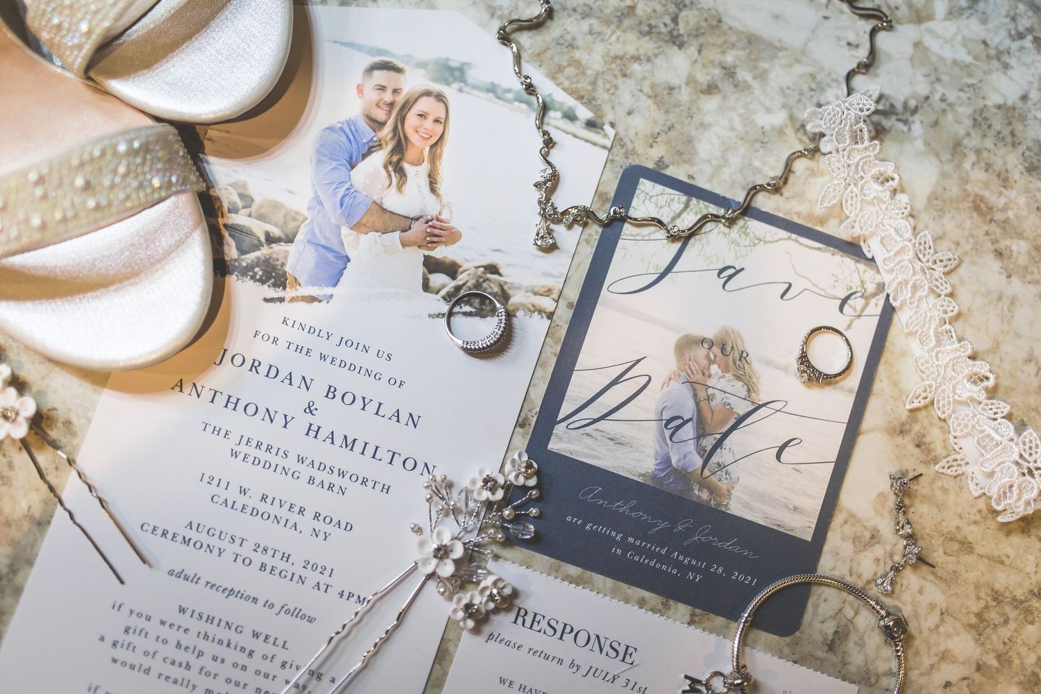 Wedding details including invitation, rings, and shoes arranged on a textured surface.