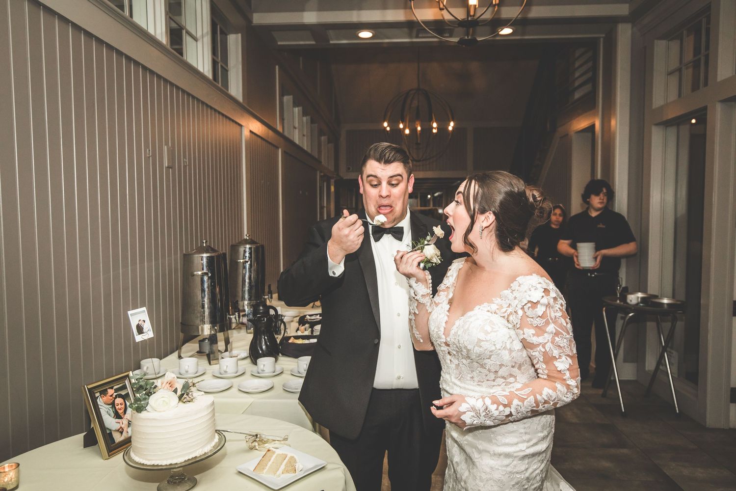 Couple feeds each other wedding cake during their reception celebration.