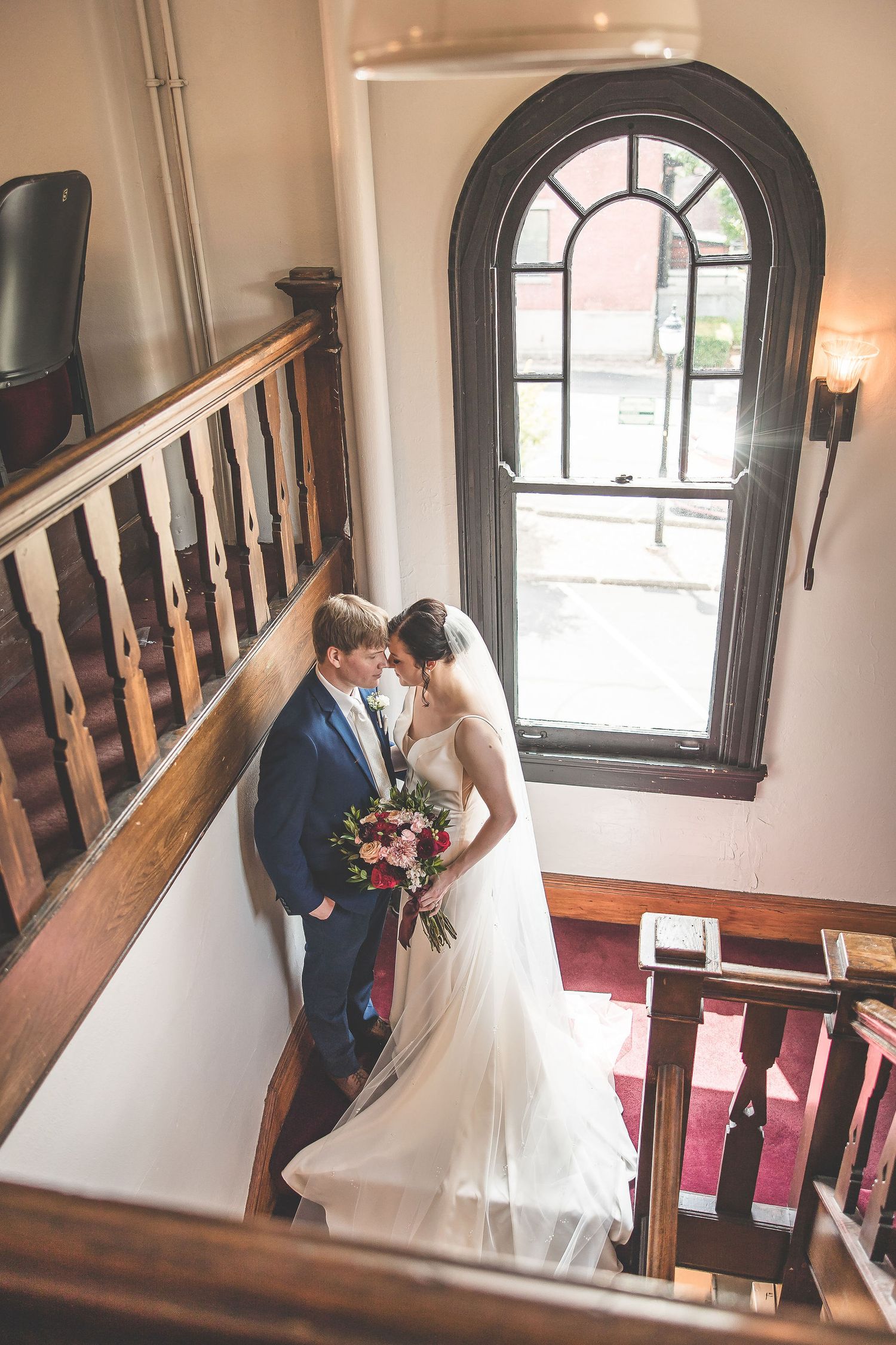 Wedding couple photographed in an ornate theater with classic architectural elements and natural light.