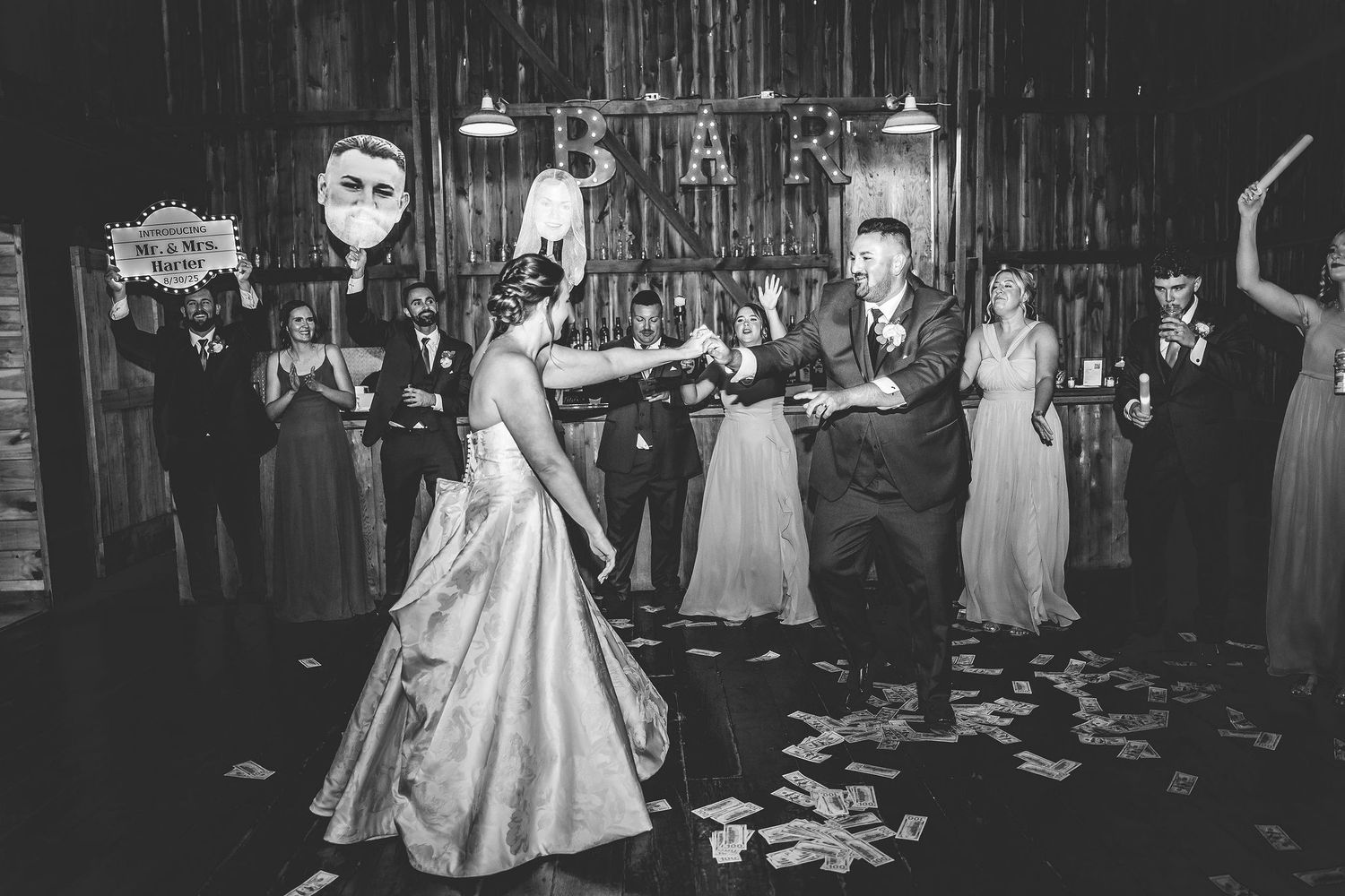 Black and white photo of wedding celebration in rustic barn with dancing guests.