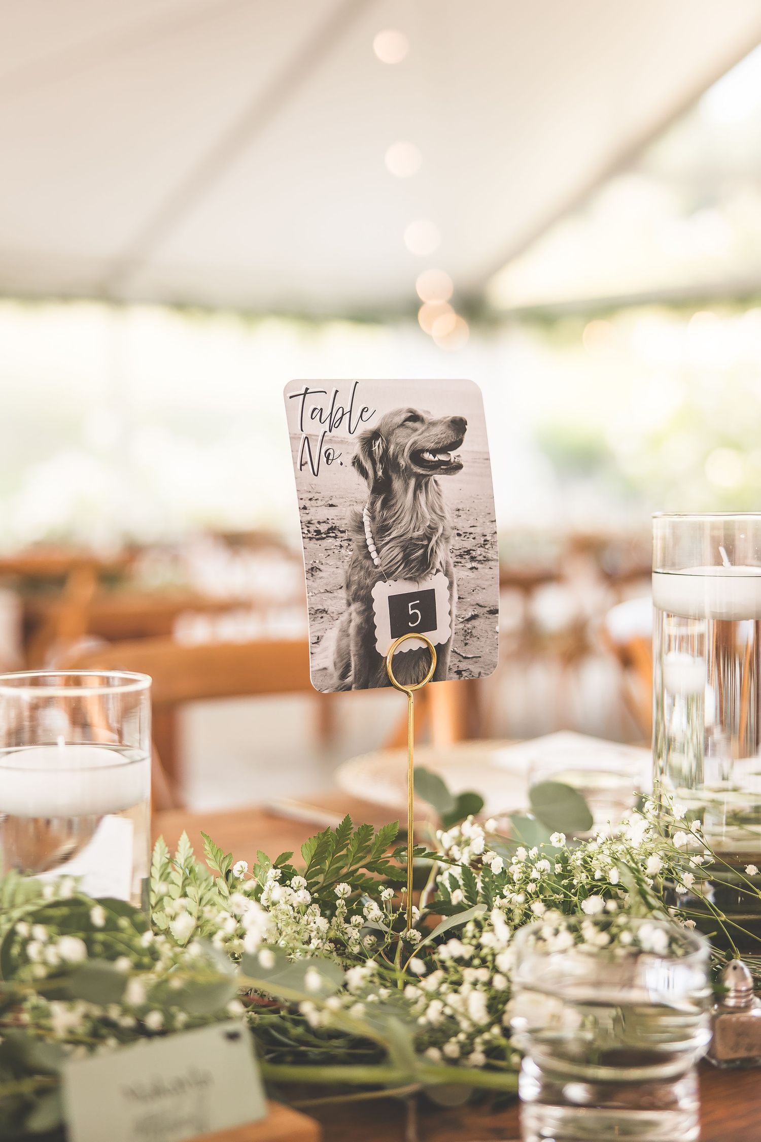 Wedding table settings with delicate greenery garlands and vintage-style table number cards.
