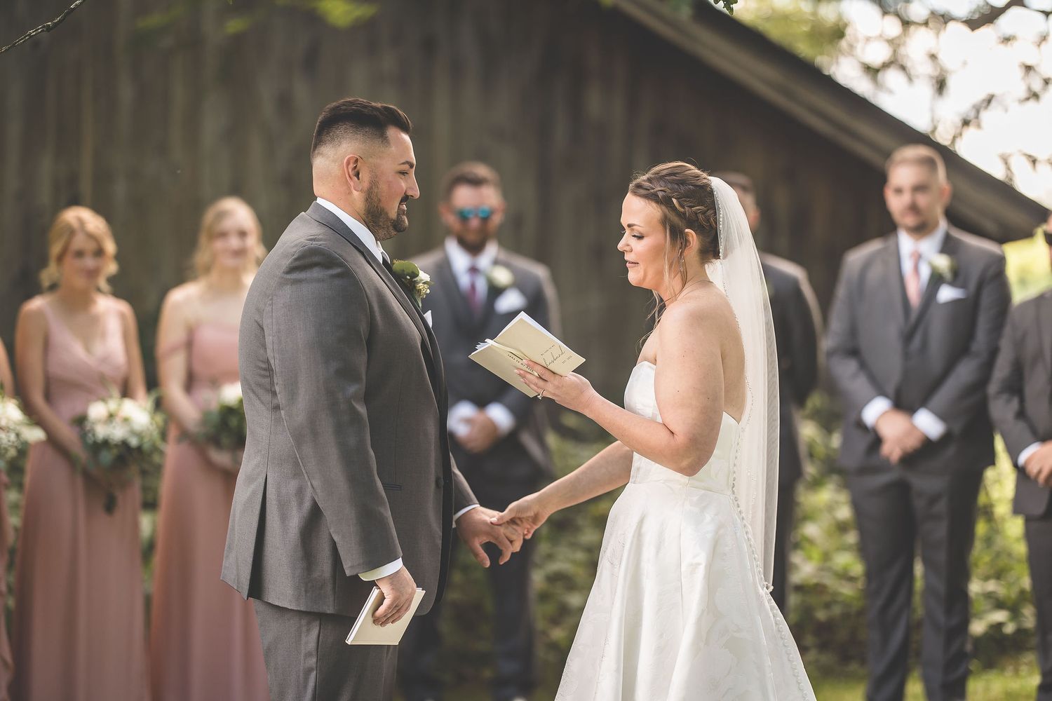 Wedding ceremony participants reading from books during an outdoor service.