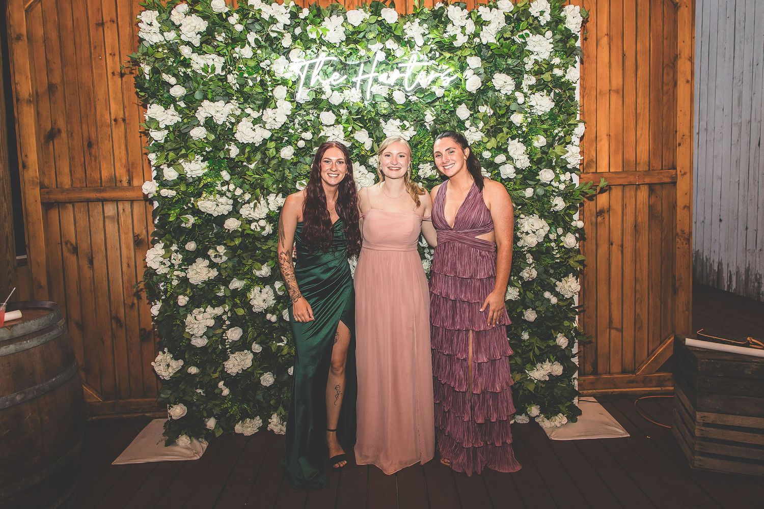 Wedding photo backdrop with white floral wall and wooden panels in a rustic venue.