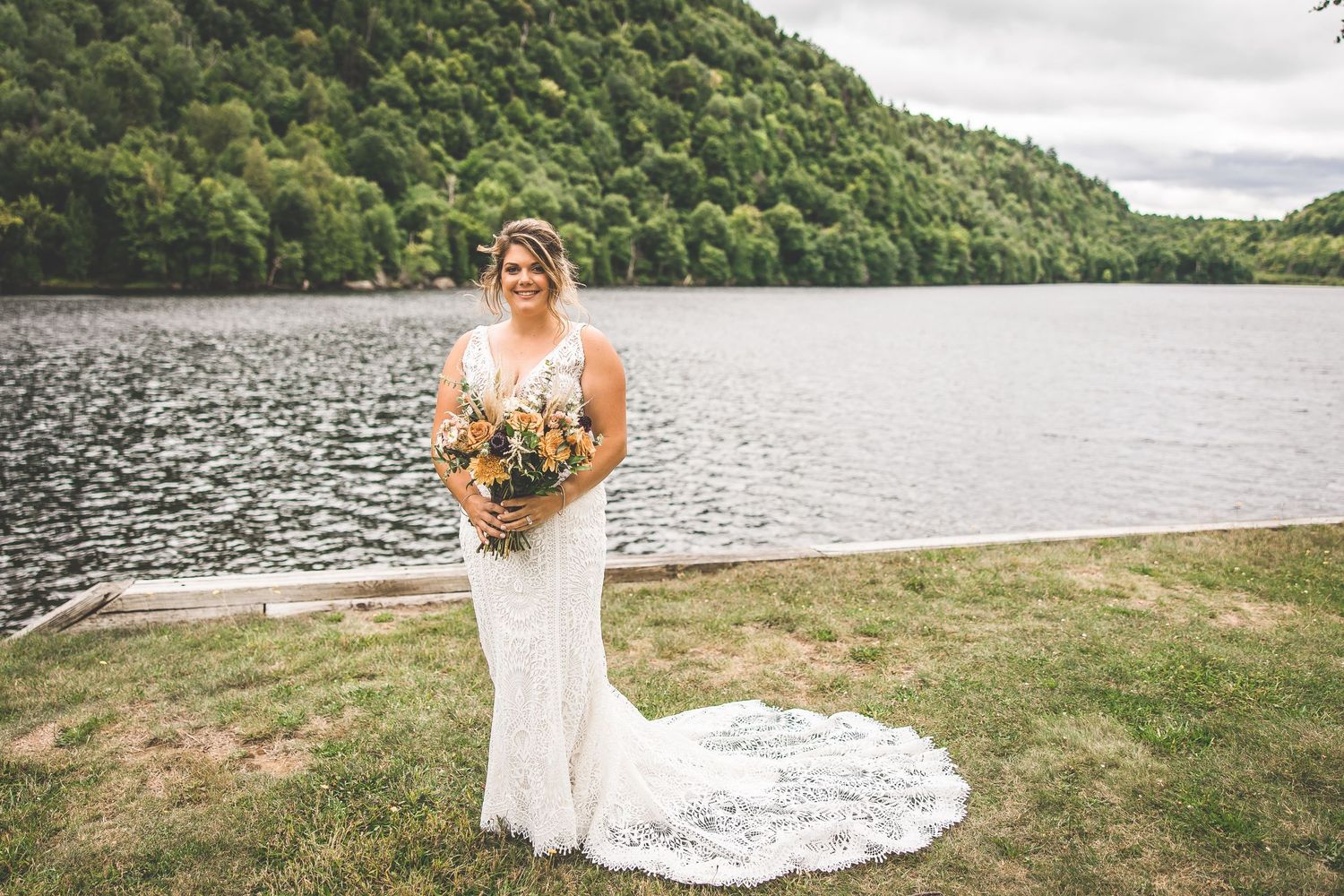 Scenic mountain lake surrounded by lush green slopes provides backdrop for outdoor wedding.