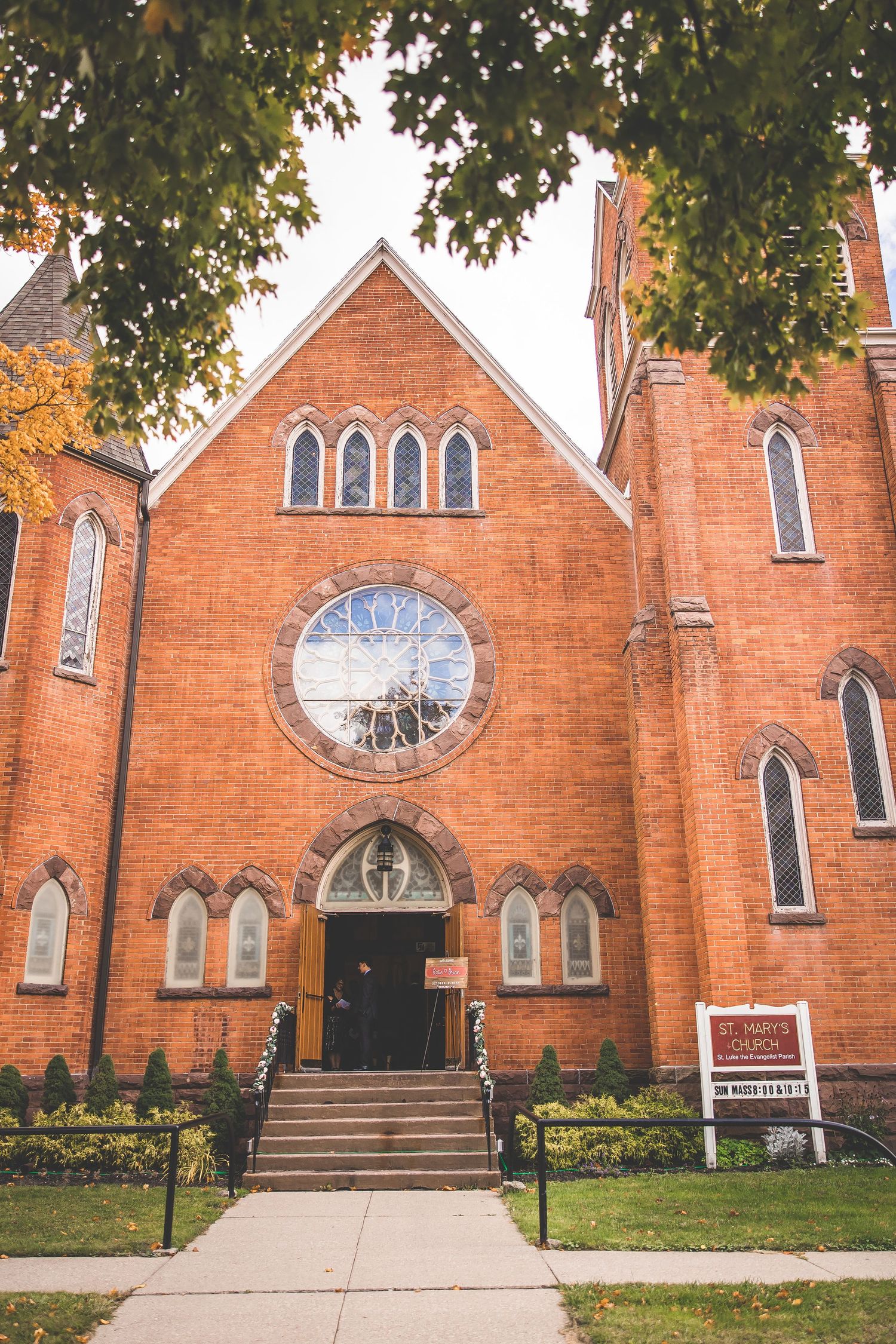 Exterior view of a red brick church with Gothic arched windows and multiple entrances.