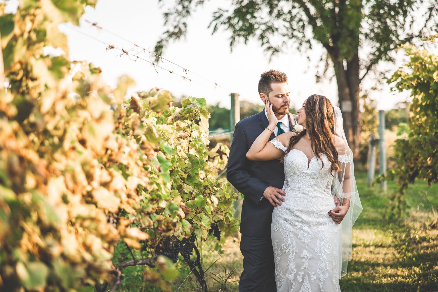 Romantic outdoor wedding photoshoot with couple embracing in golden sunlight and autumn foliage.