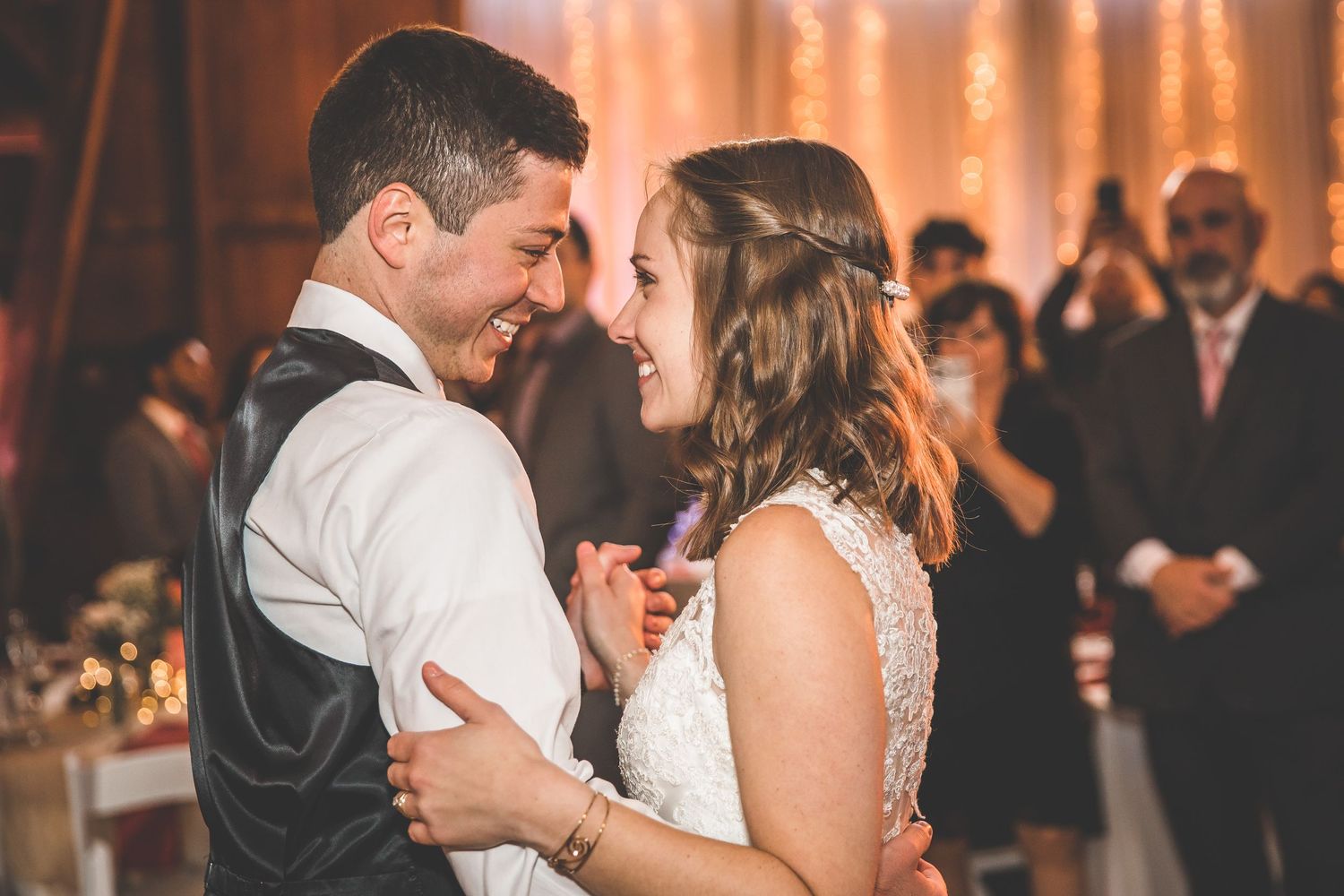 Couples dancing together during romantic evening wedding reception with warm ambient lighting.