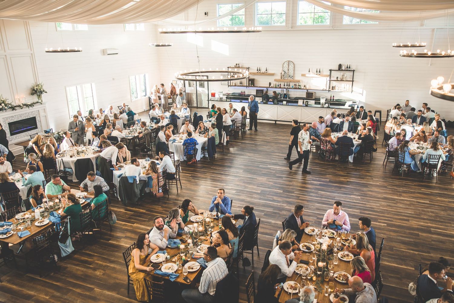 Panoramic view of wedding reception hall with guests seated at long tables.