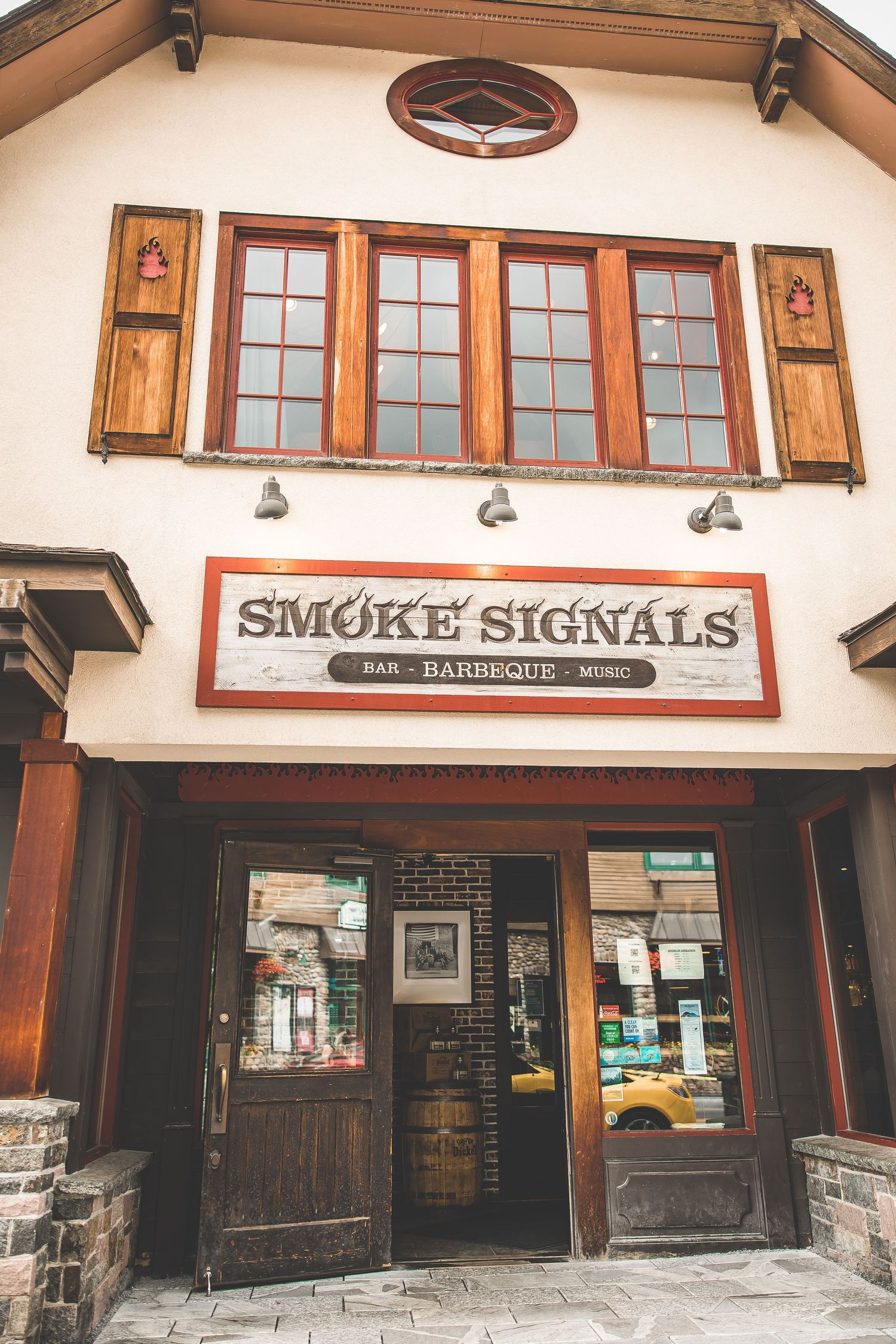 Exterior view of Smoke Signals restaurant with rustic wooden trim and windows.