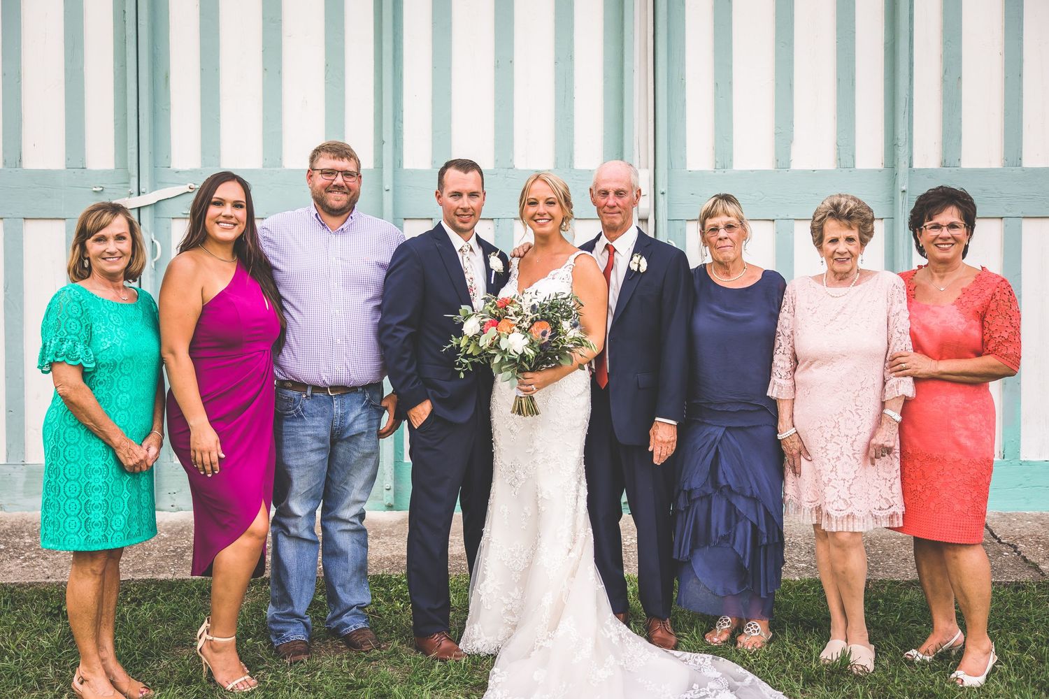 Family and wedding party formal portrait against mint striped backdrop.