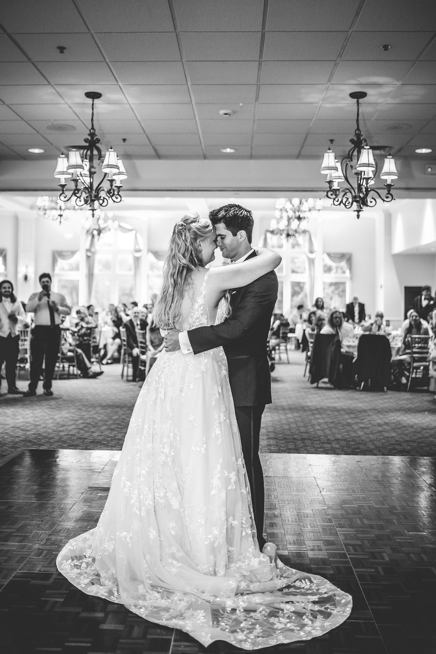 Black and white photo of a romantic first dance with a bride's lace dress trailing behind.