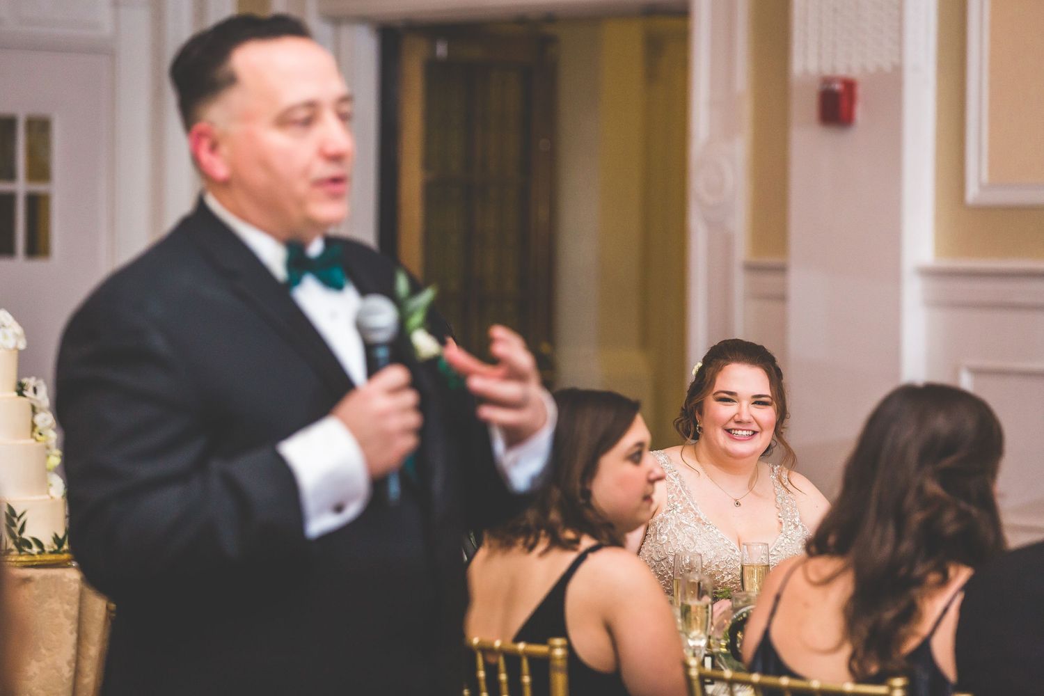 Wedding reception guests enjoying speeches and toasts in an elegant ballroom setting.