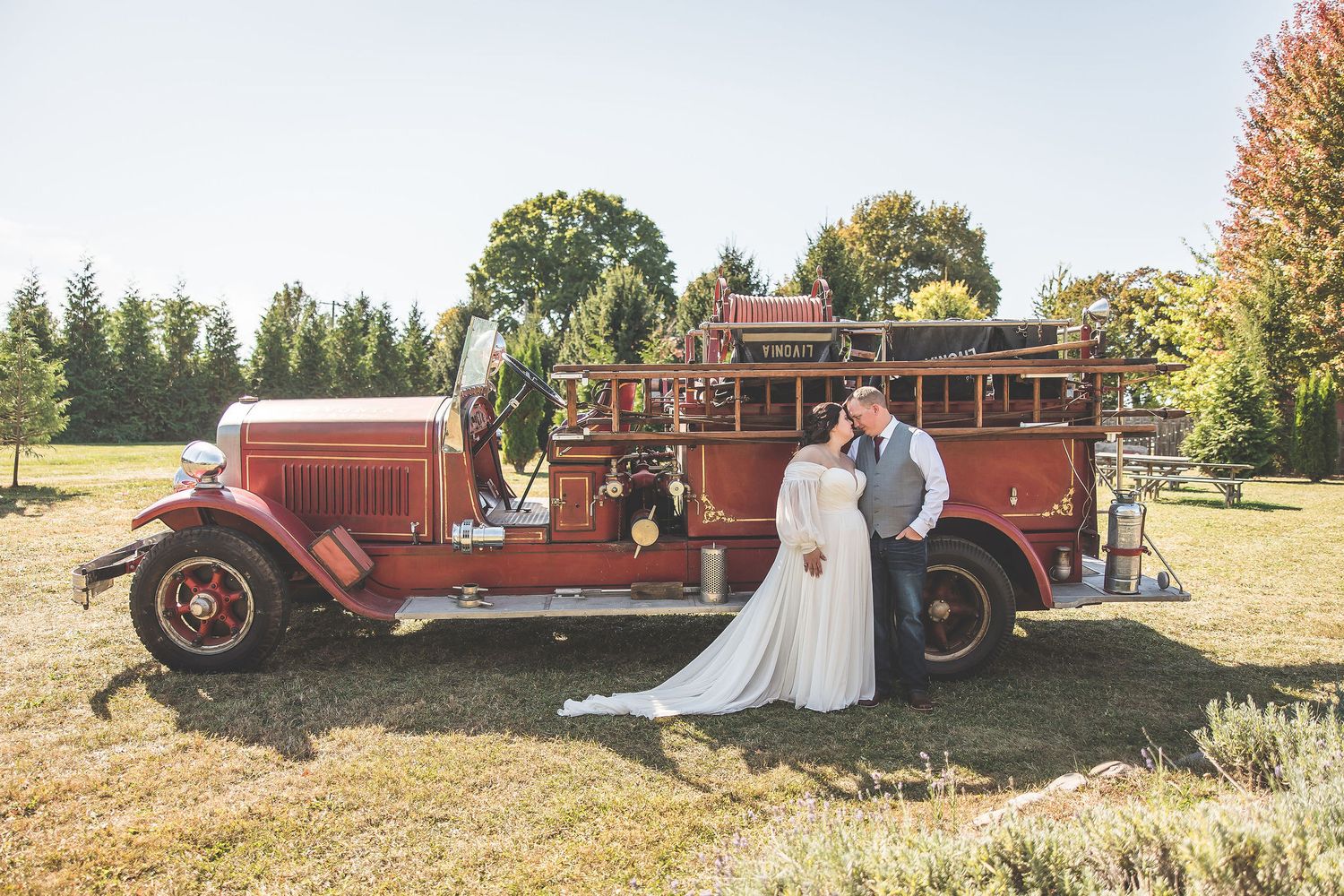 Classic red fire truck serves as unique prop for outdoor wedding photography.