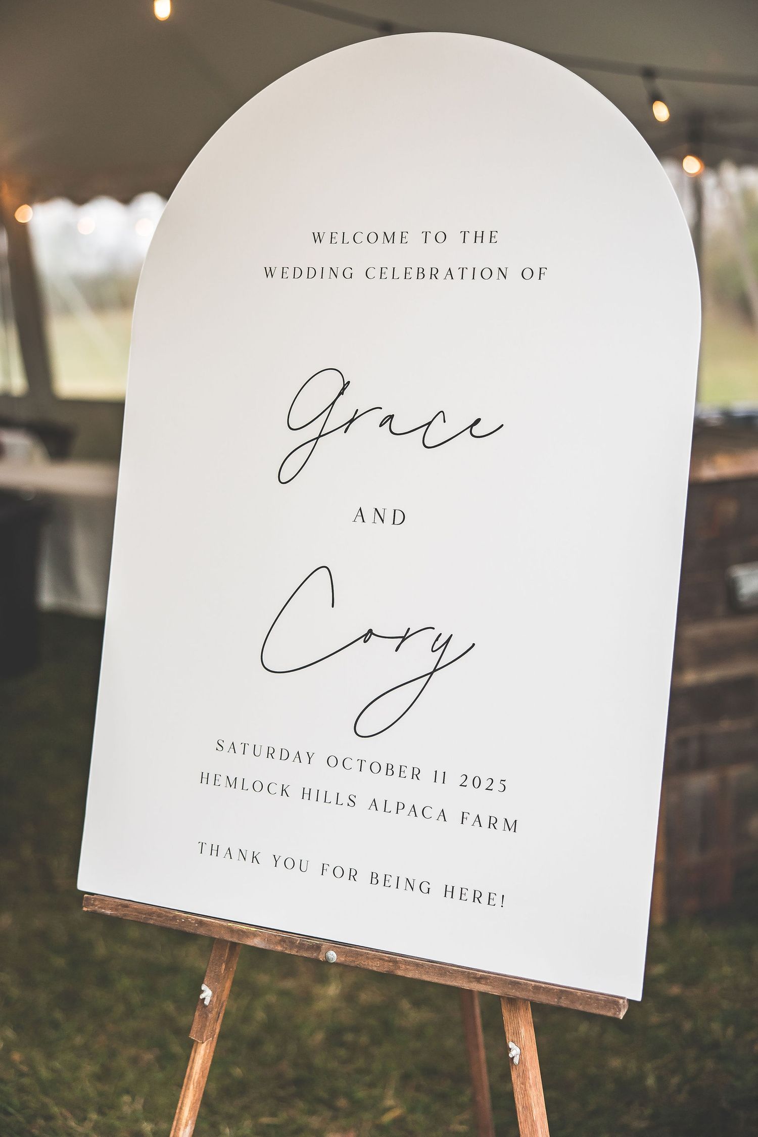Elegant wedding welcome sign displayed on an easel at an outdoor venue.