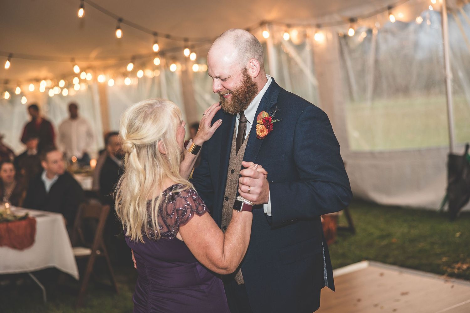 Couples dancing together at an evening wedding reception under warm string lighting.