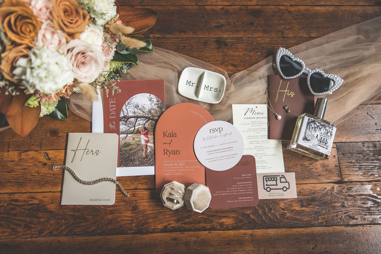 Elegant wedding stationery and invitations in coral and white tones displayed on dark wood.
