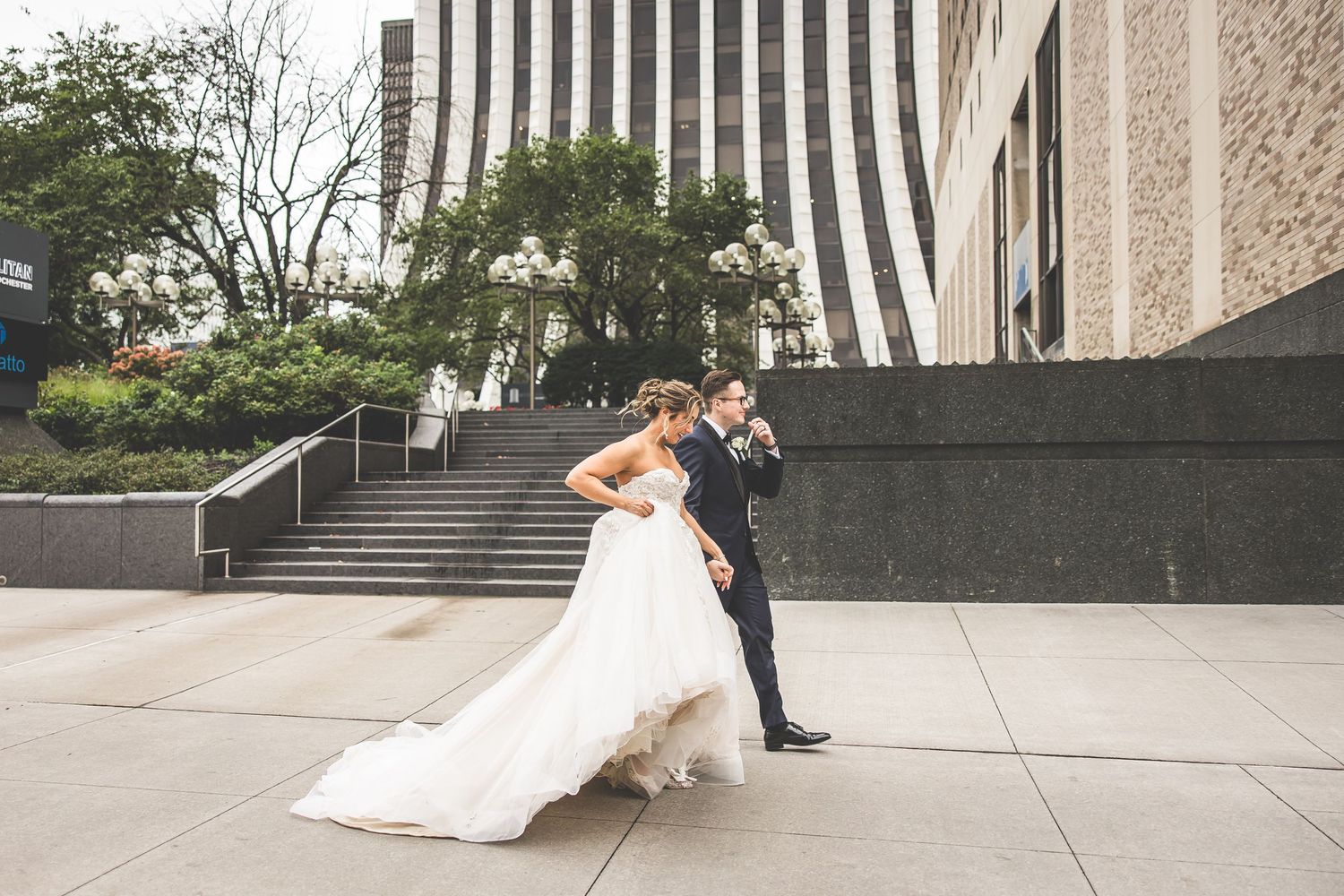 A wedding couple poses dramatically on outdoor stone steps at an elegant venue.