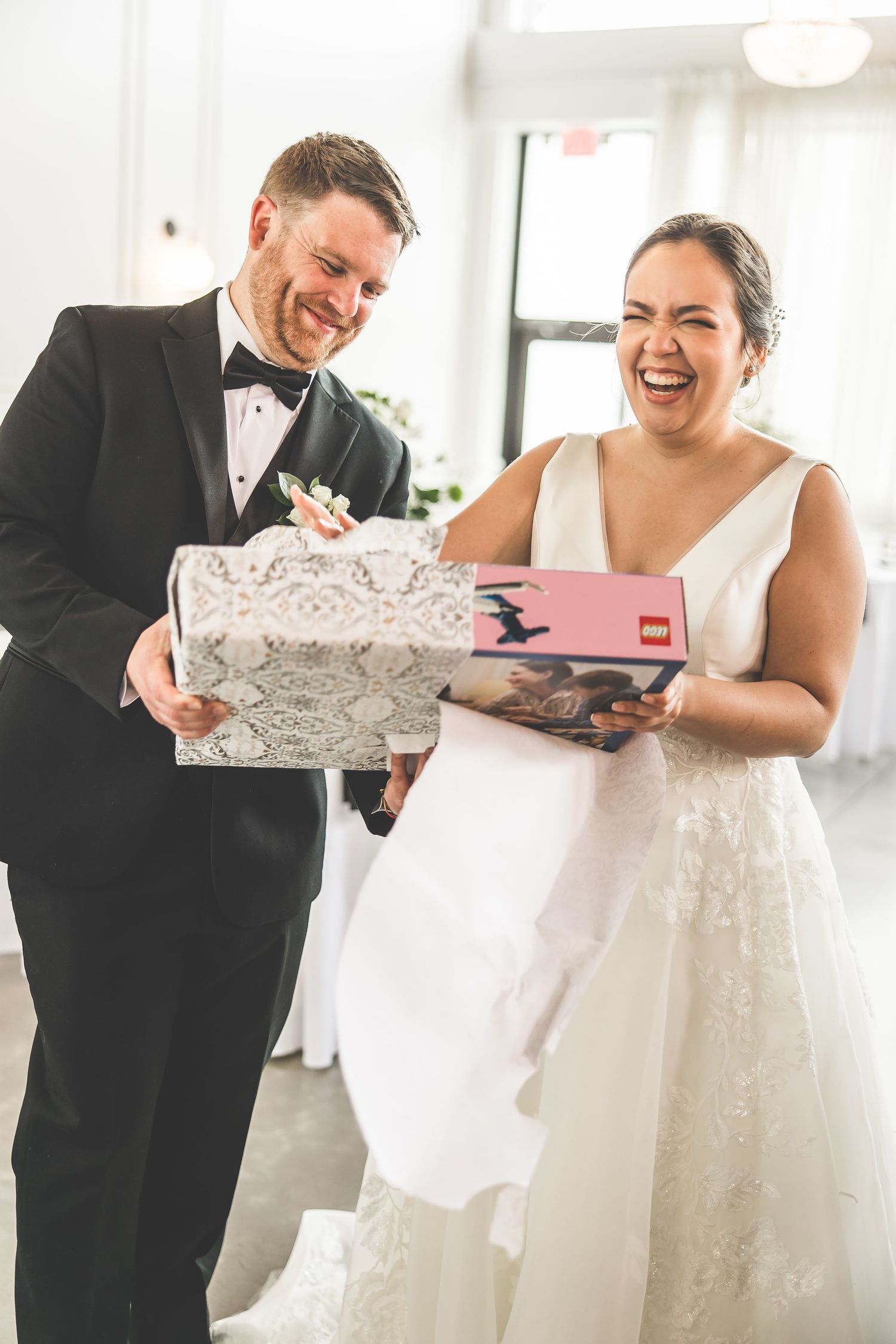 Couple opens wedding gifts together in a bright indoor setting.