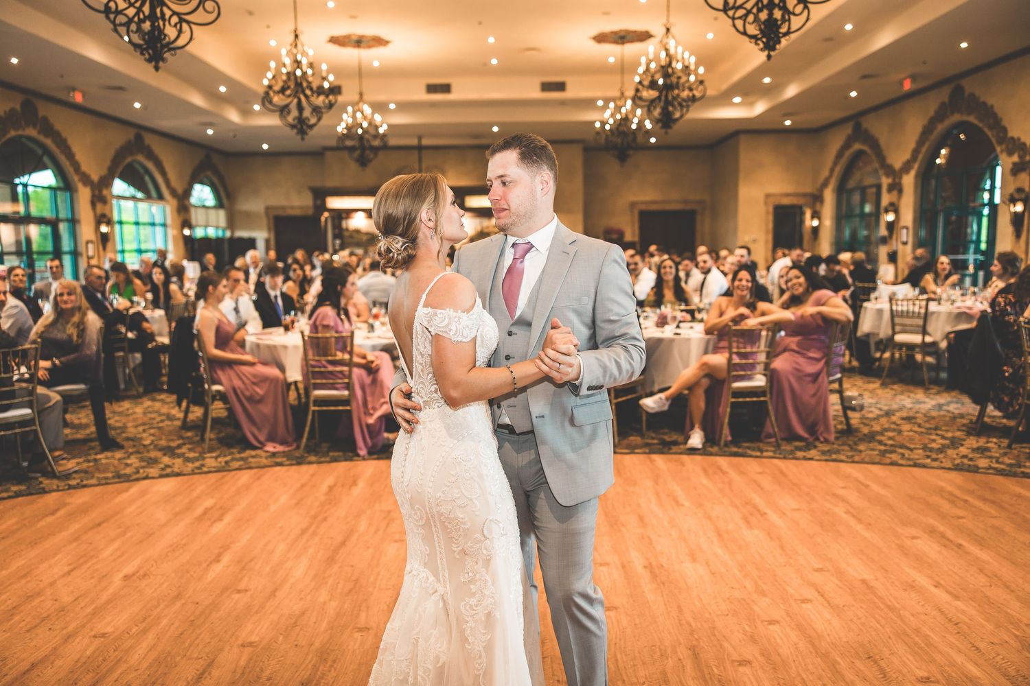 Wedding reception venue with ornate chandeliers and arched windows creating a romantic atmosphere.
