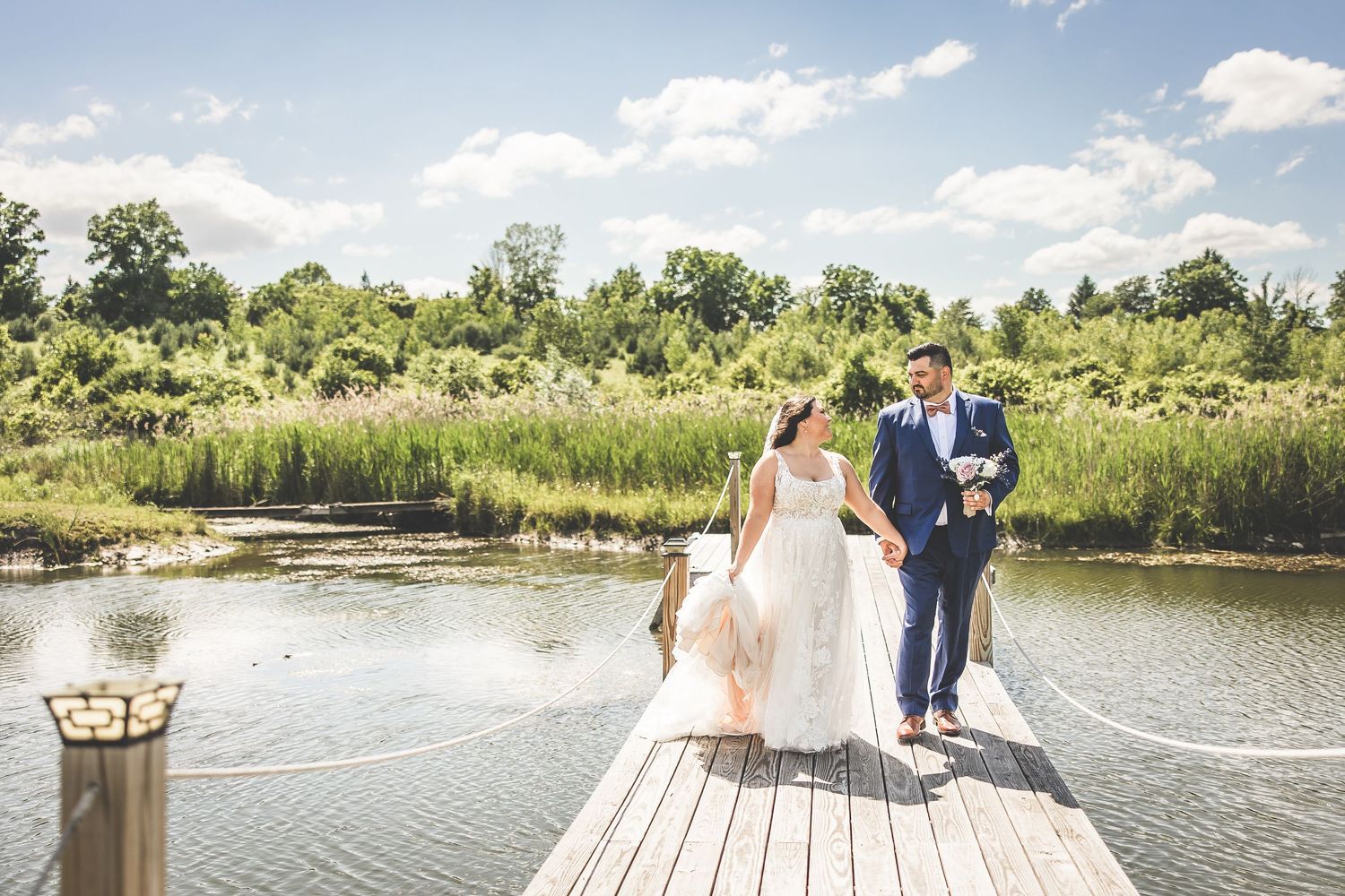 Panoramic wedding photos by a serene lake with wooden dock and natural landscape.