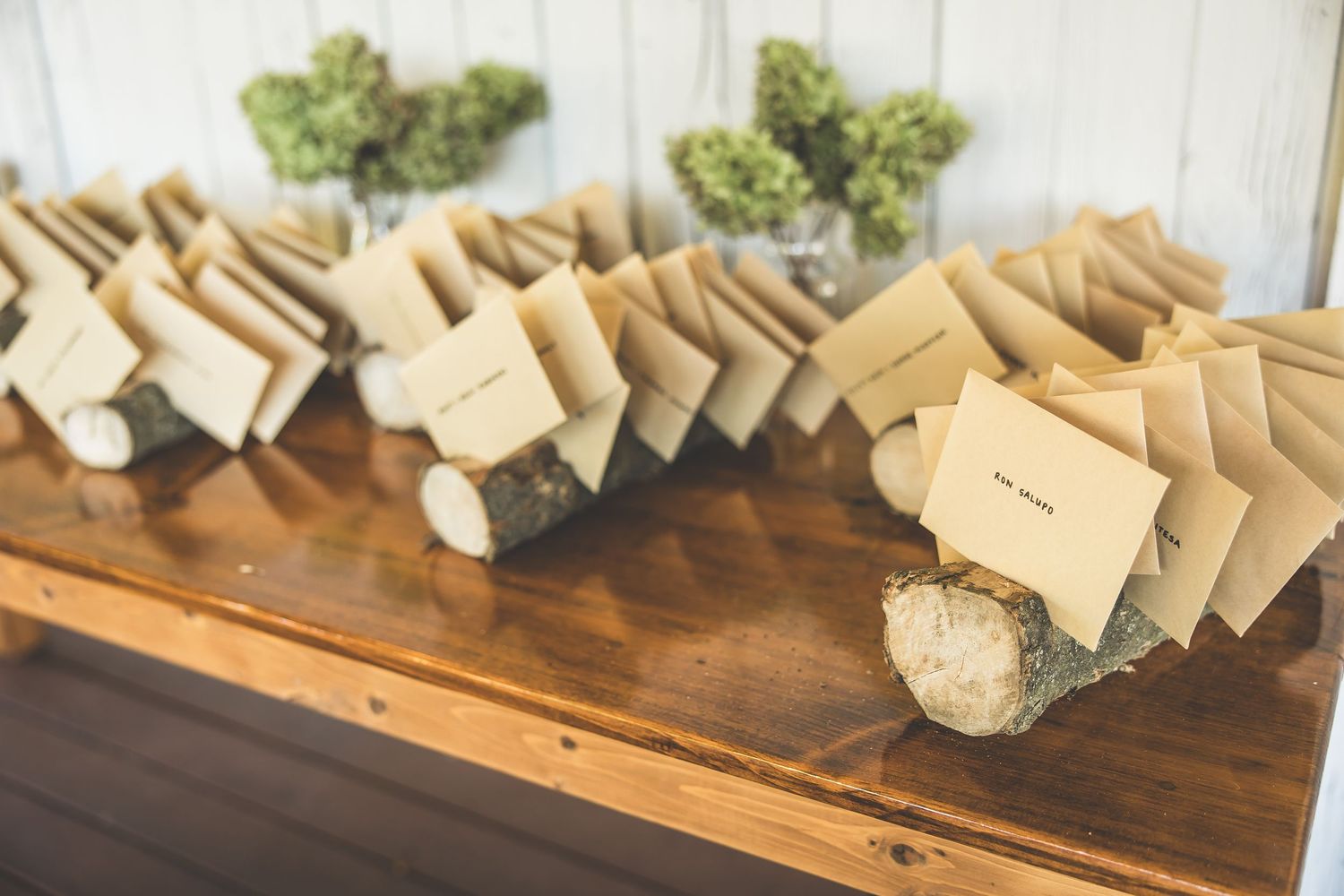 Place cards and table settings arranged on a rustic wooden surface with greenery accents.