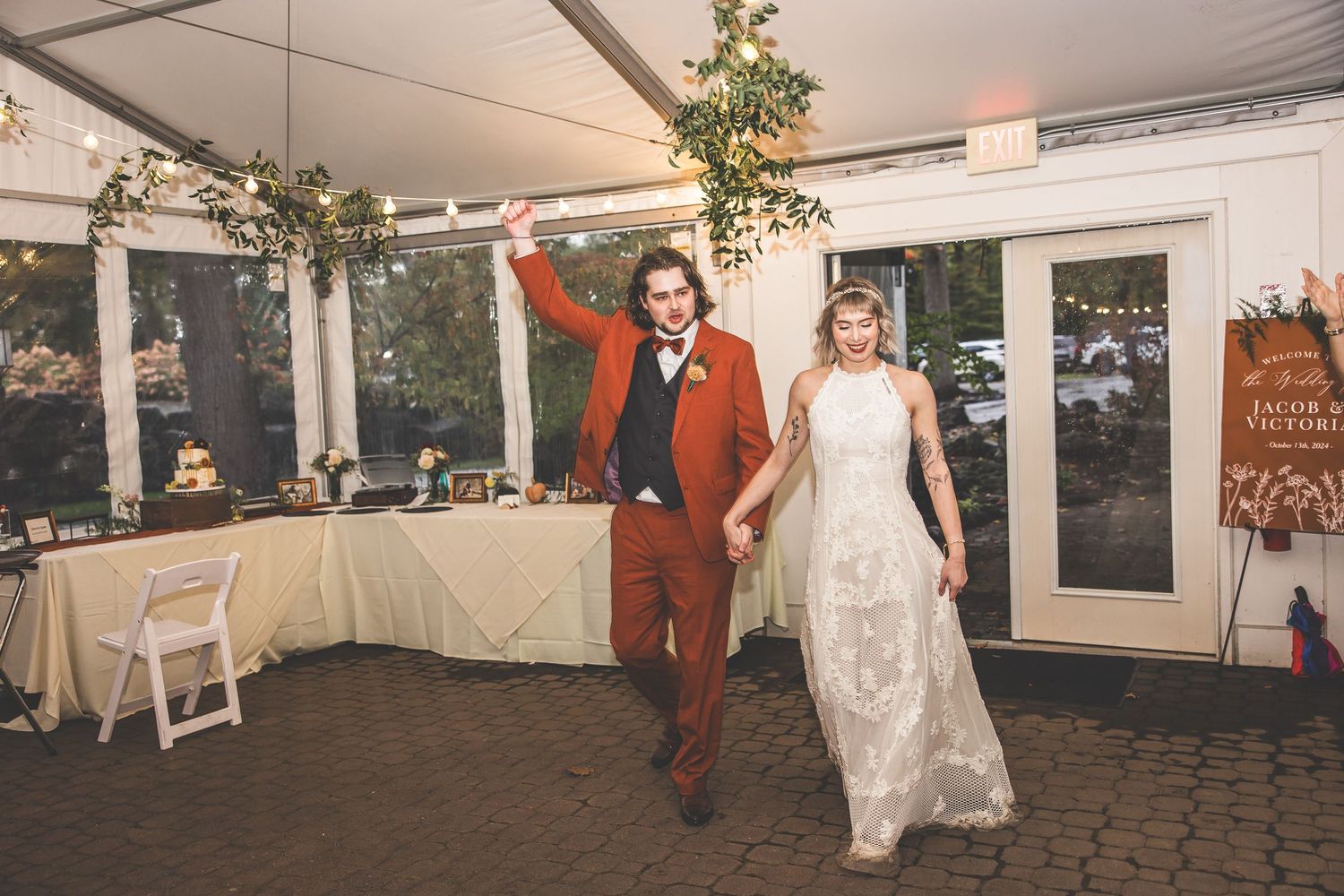 Wedding reception venue decorated with string lights and floral arrangements under a white tent.