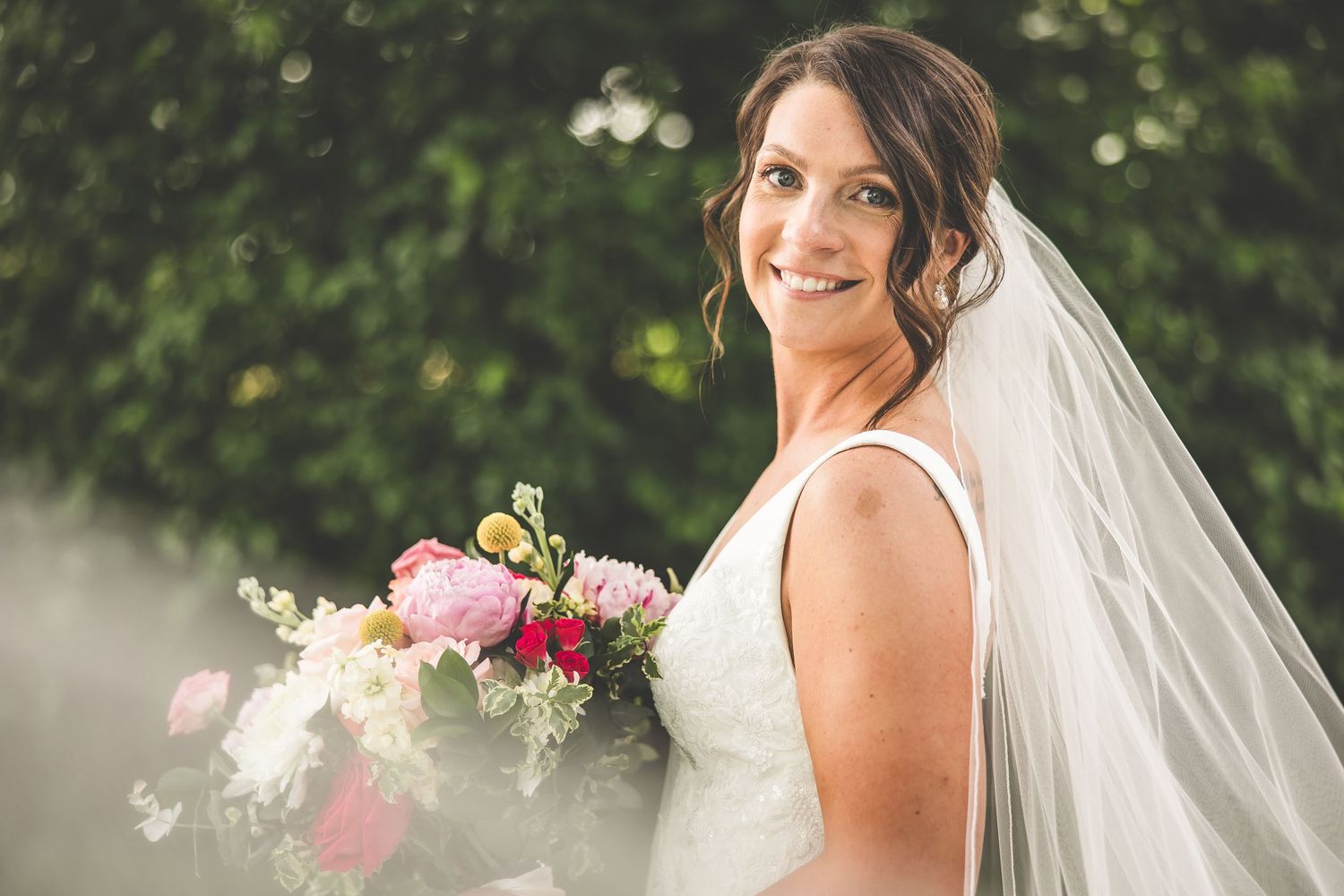 Bridal portraits in a lush garden setting featuring a flowing white wedding gown and pink bouquet.