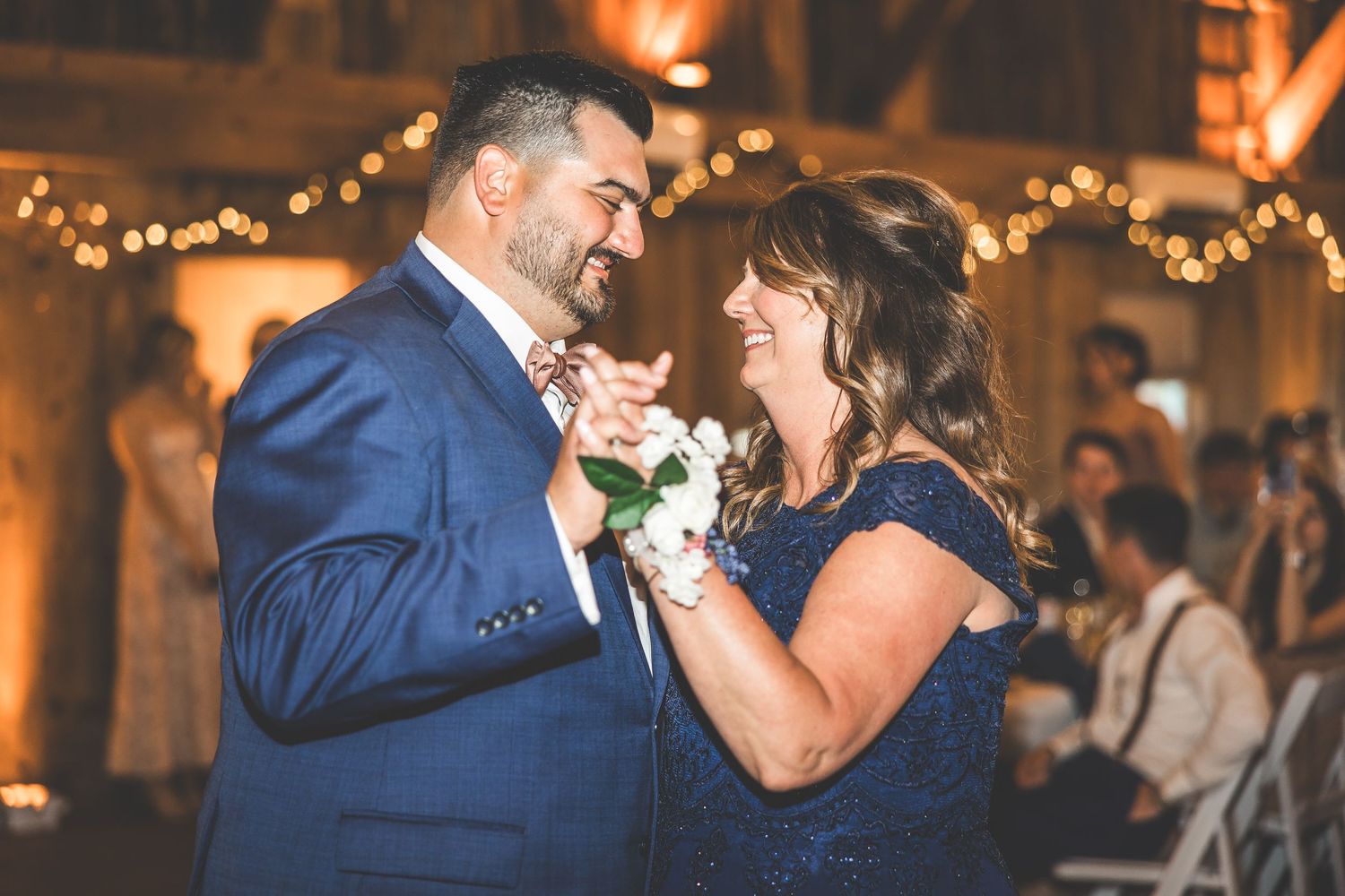 Wedding reception dance in rustic barn venue with warm lighting and string lights.