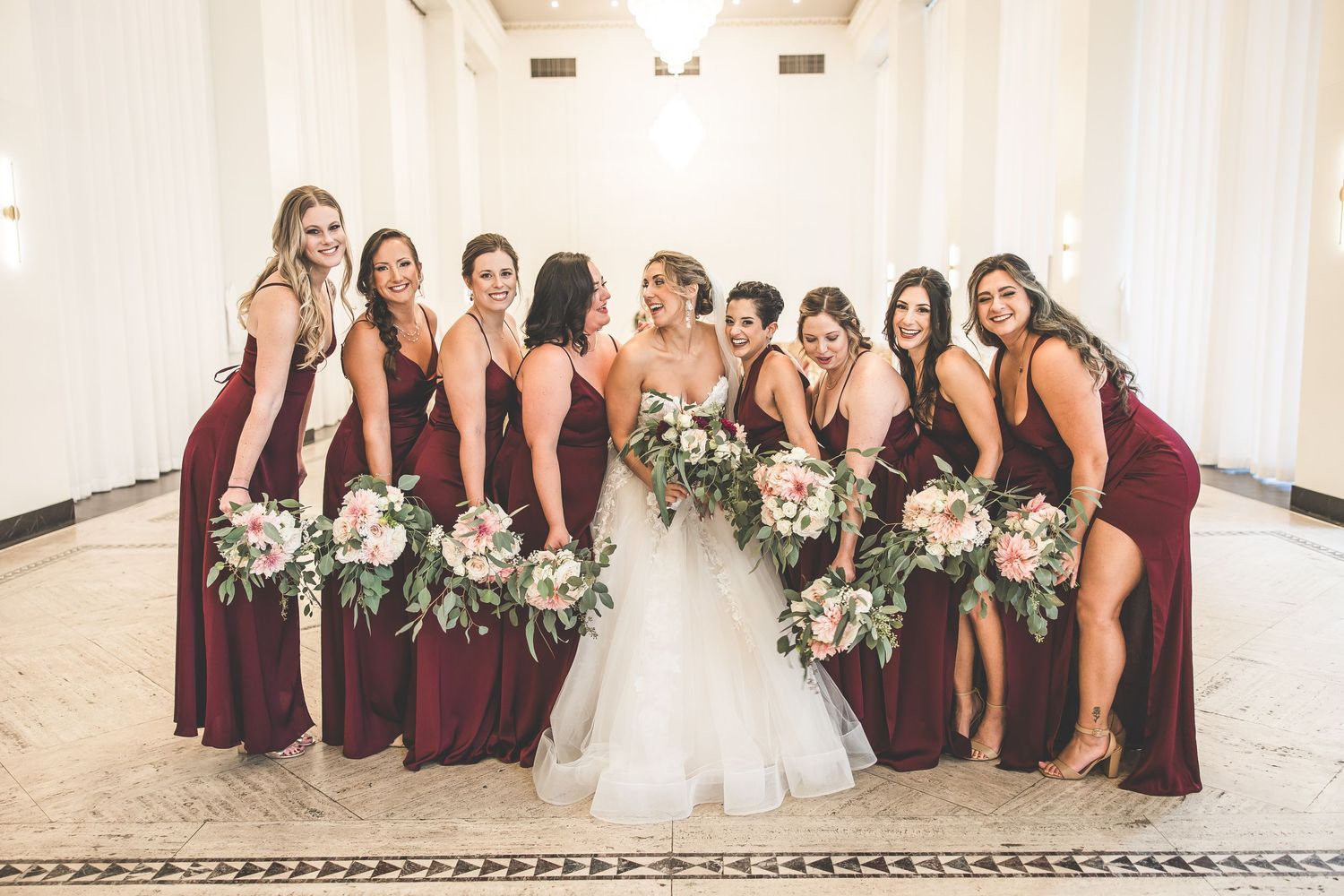 Wedding party in burgundy and navy attire poses for formal group photos.