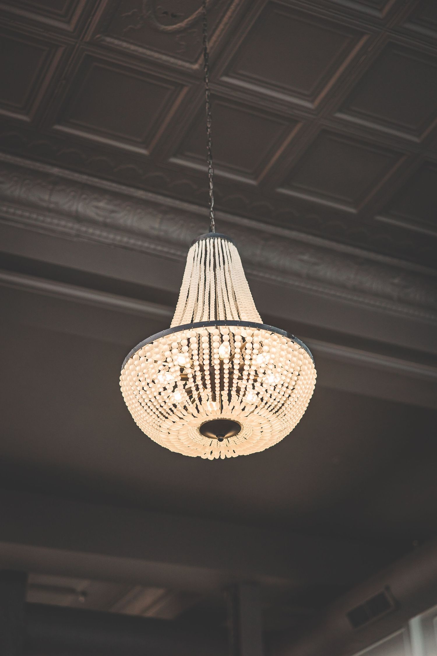 Crystal chandeliers hanging from an ornate ceiling create elegant ambient lighting in an event space.