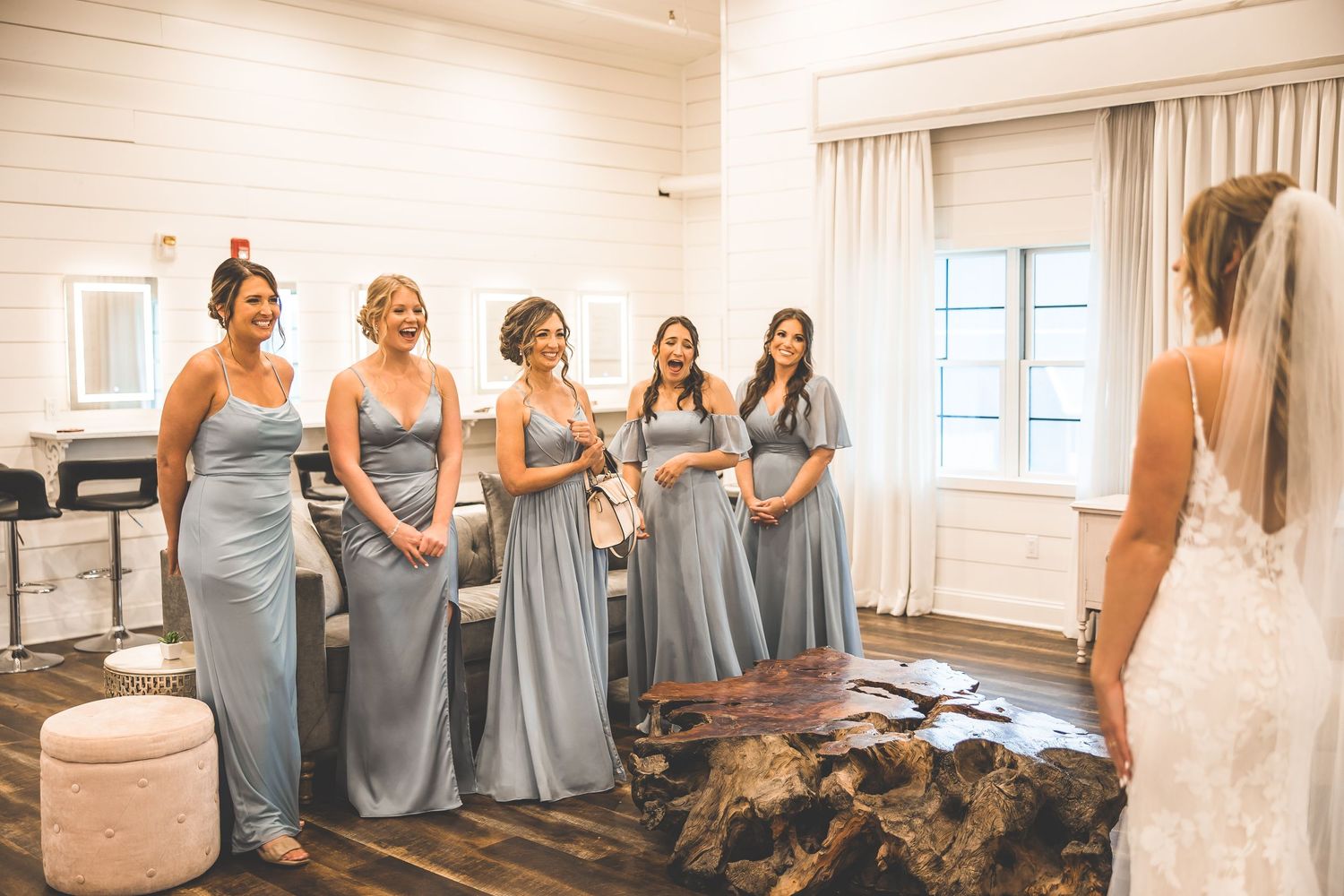 Bridesmaids in dusty blue dresses share emotional moments while getting ready for a wedding.