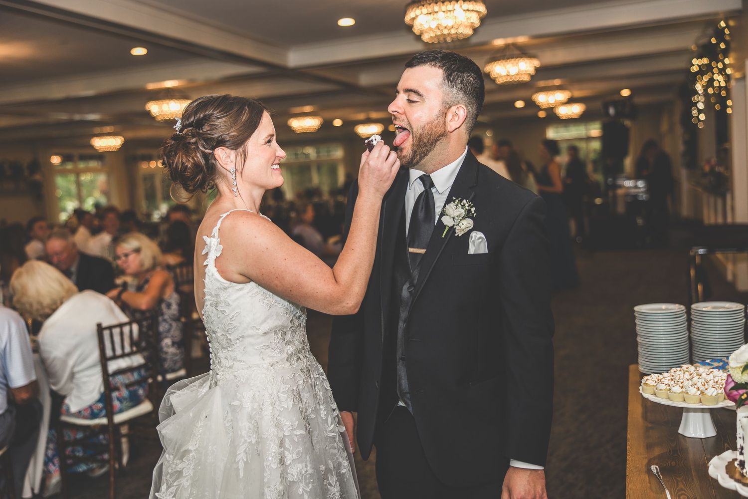 Newlyweds share playful cake-feeding moment at wedding reception.