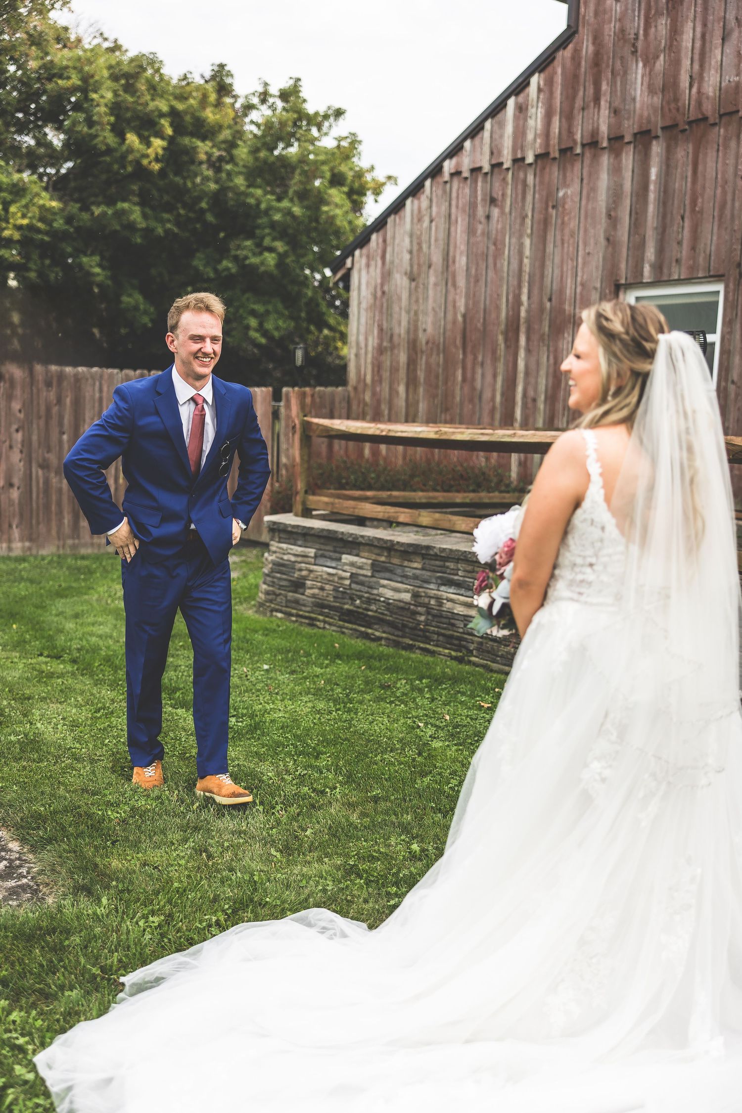 First look wedding moment captured in front of rustic barn with flowing white dress.