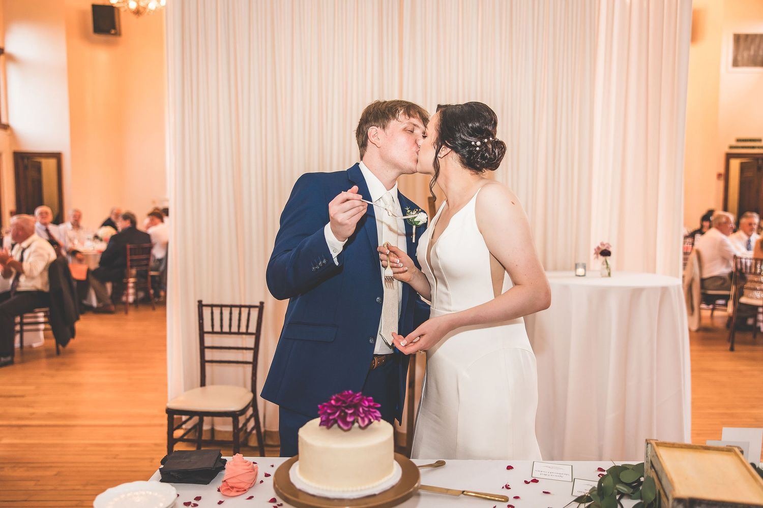 Wedding couple feeds each other cake during reception celebration.
