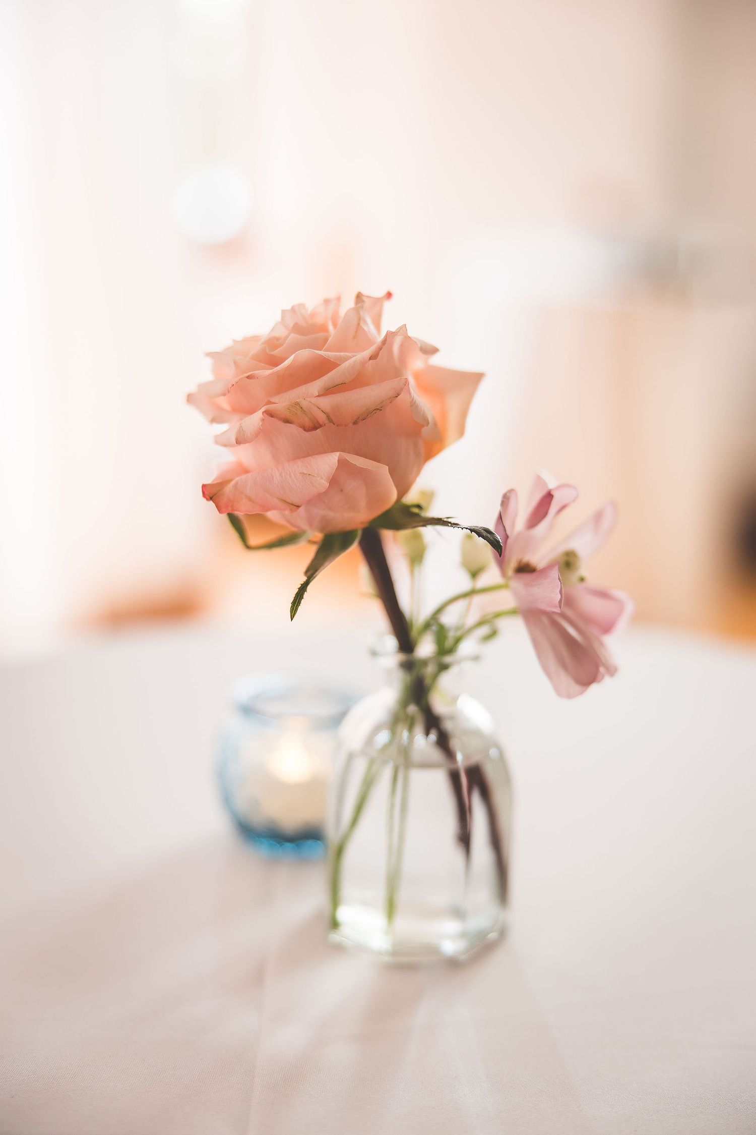 Delicate pink roses in small glass vases create an elegant table centerpiece display.