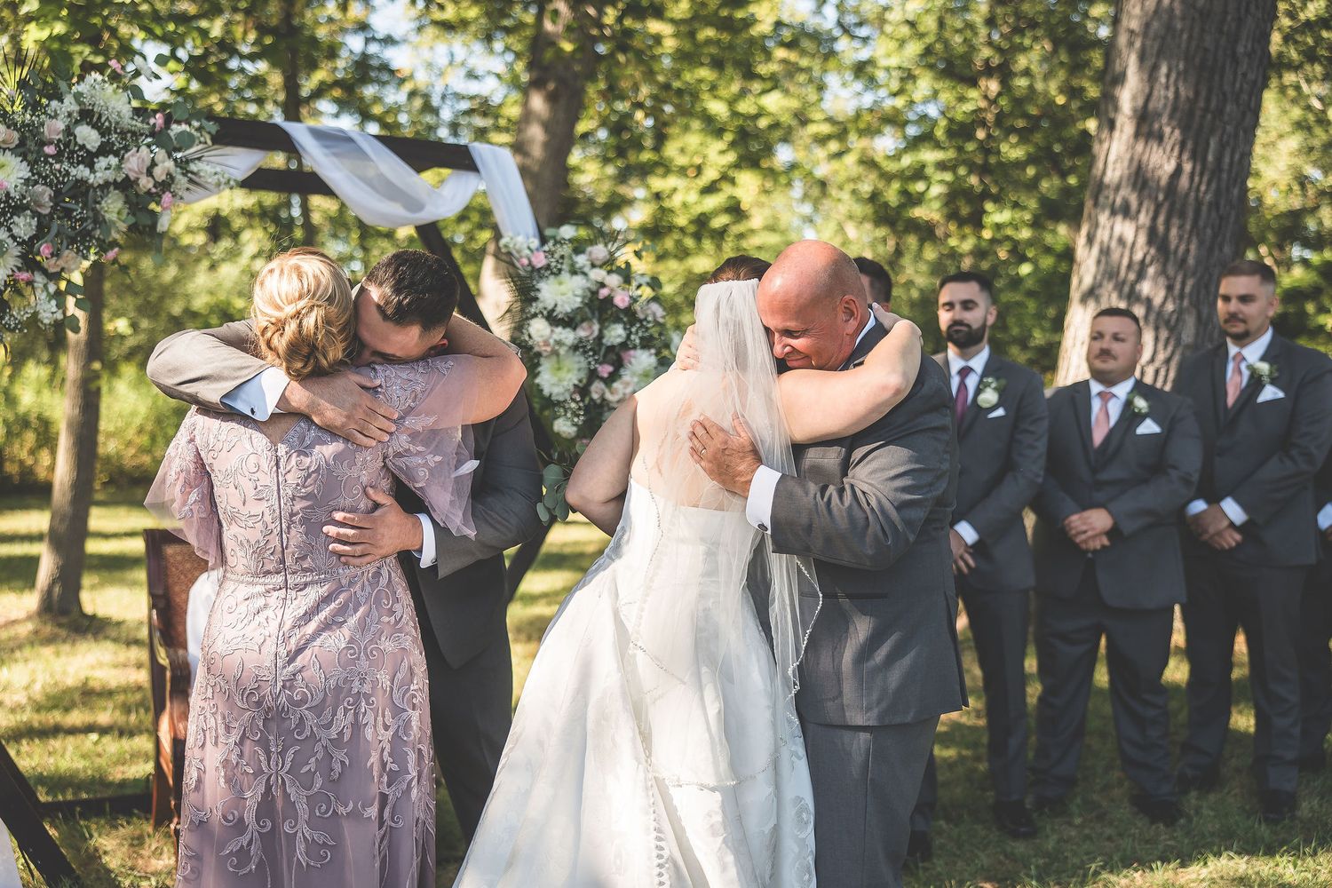 Emotional moments during outdoor wedding ceremony with guests watching.