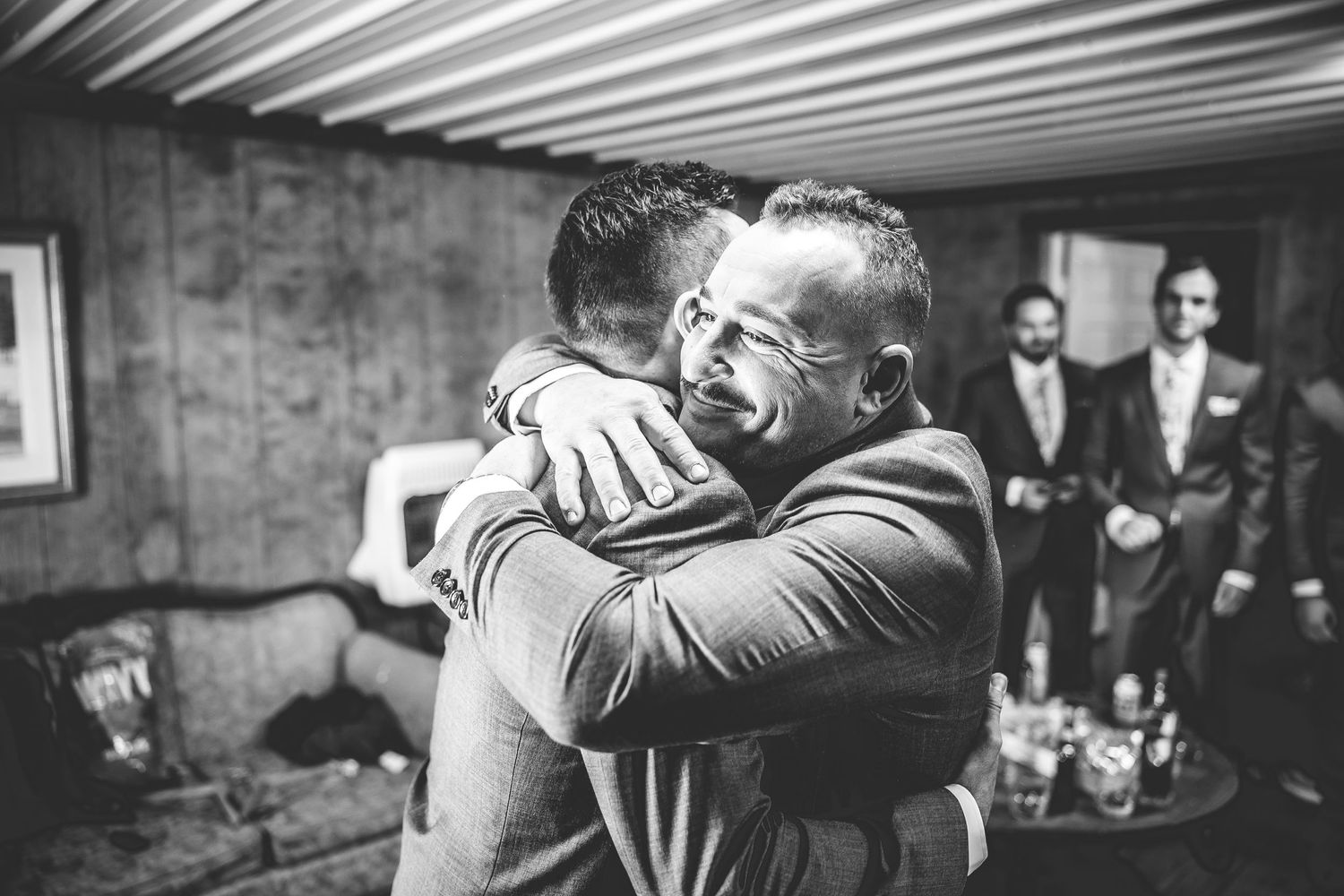 Black and white emotional embrace captured during wedding preparation.