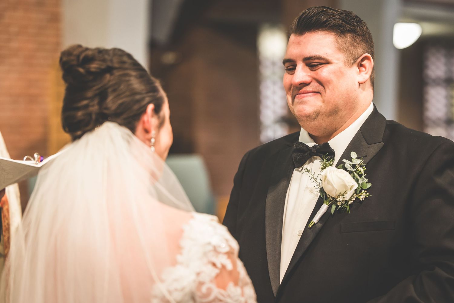 Couple shares an intimate moment during their wedding ceremony in a traditional church setting.