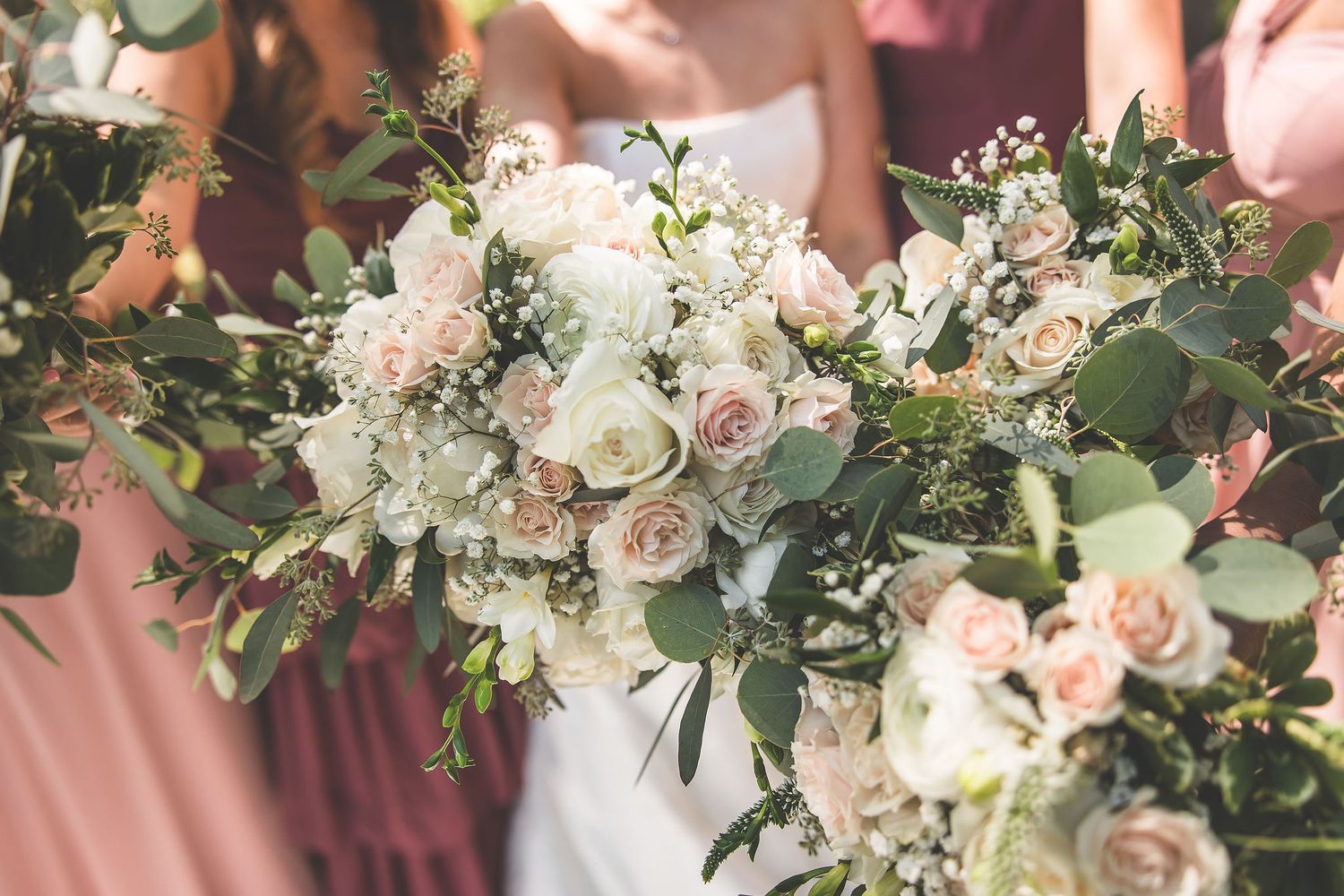 Elegant wedding bouquets featuring blush roses and mixed greenery.