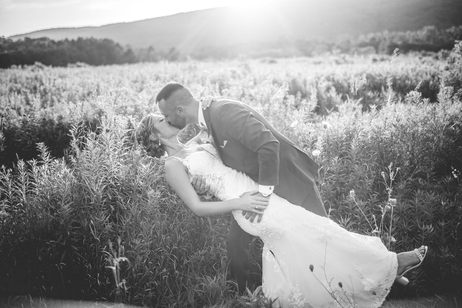 Black and white romantic wedding photos in a sunlit field.