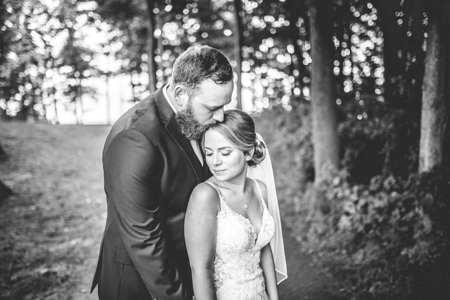 Wedding couple shares emotional moments together on a forest path in black and white.