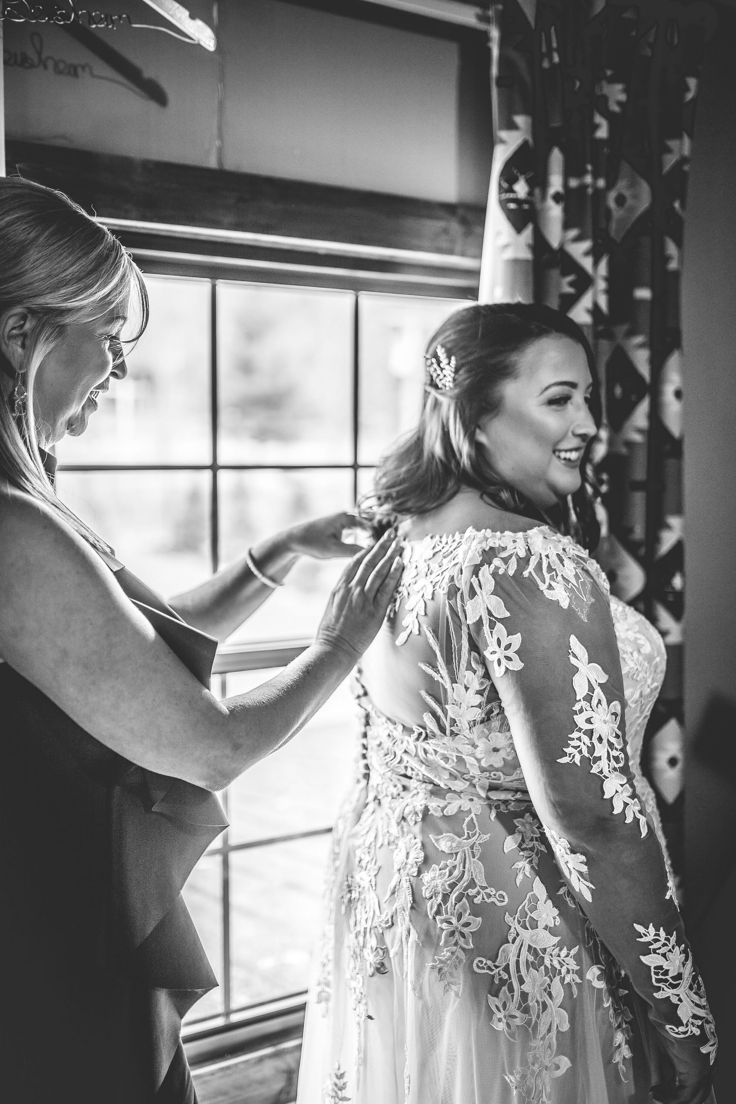 Black and white image of wedding dress preparations by a window.