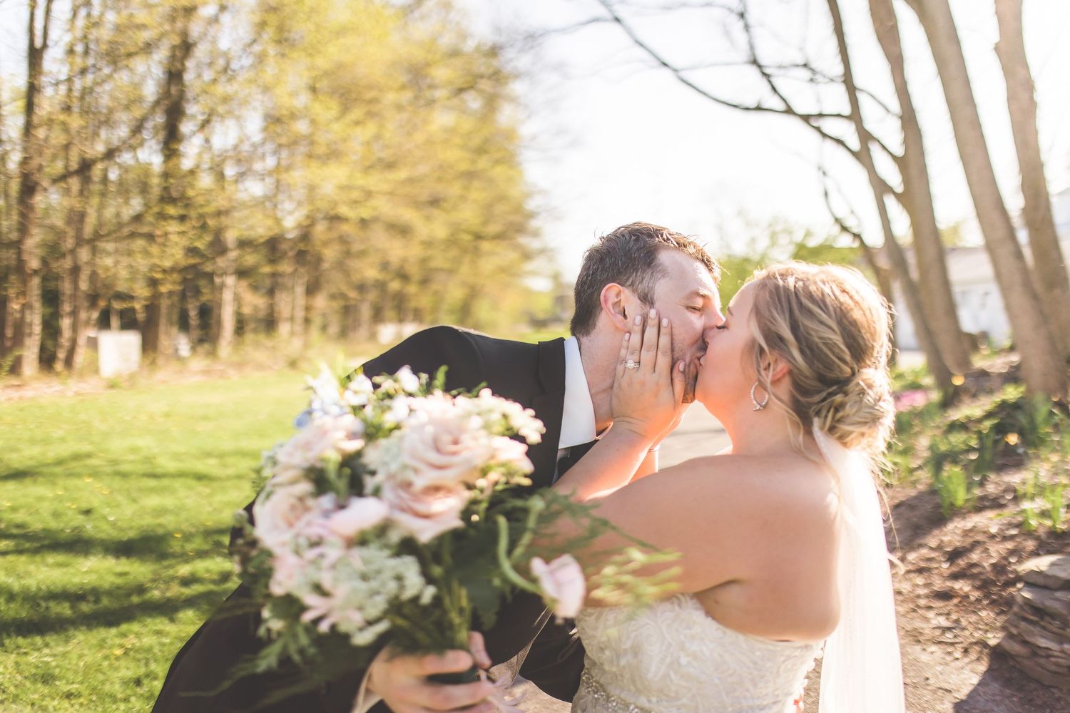 Spring wedding portraits with soft natural lighting and blooming trees in background.