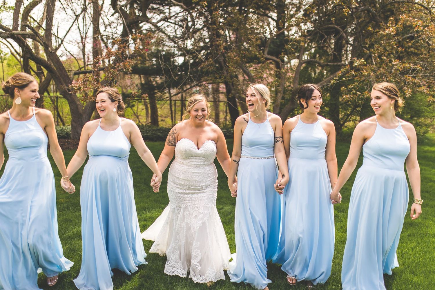 Wedding party poses outdoors with bridesmaids in flowing light blue gowns.
