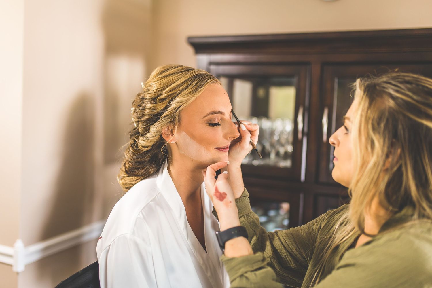 Emotional wedding party getting ready in matching white robes against rustic backdrop.
