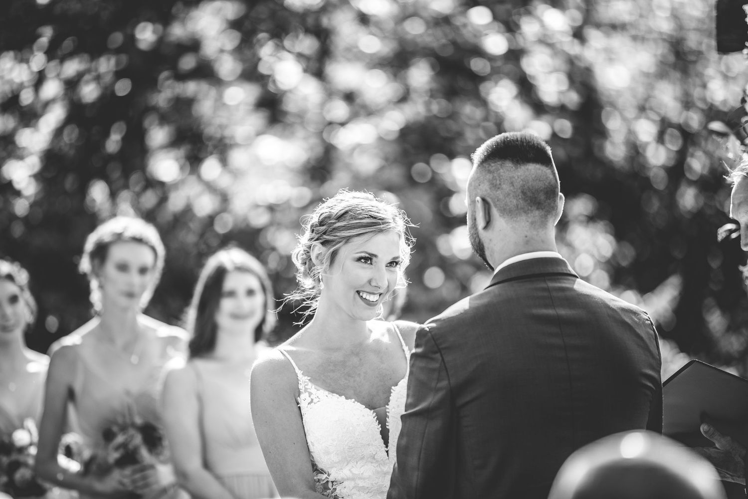 Black and white photo of wedding guests seated in rows during an outdoor ceremony.